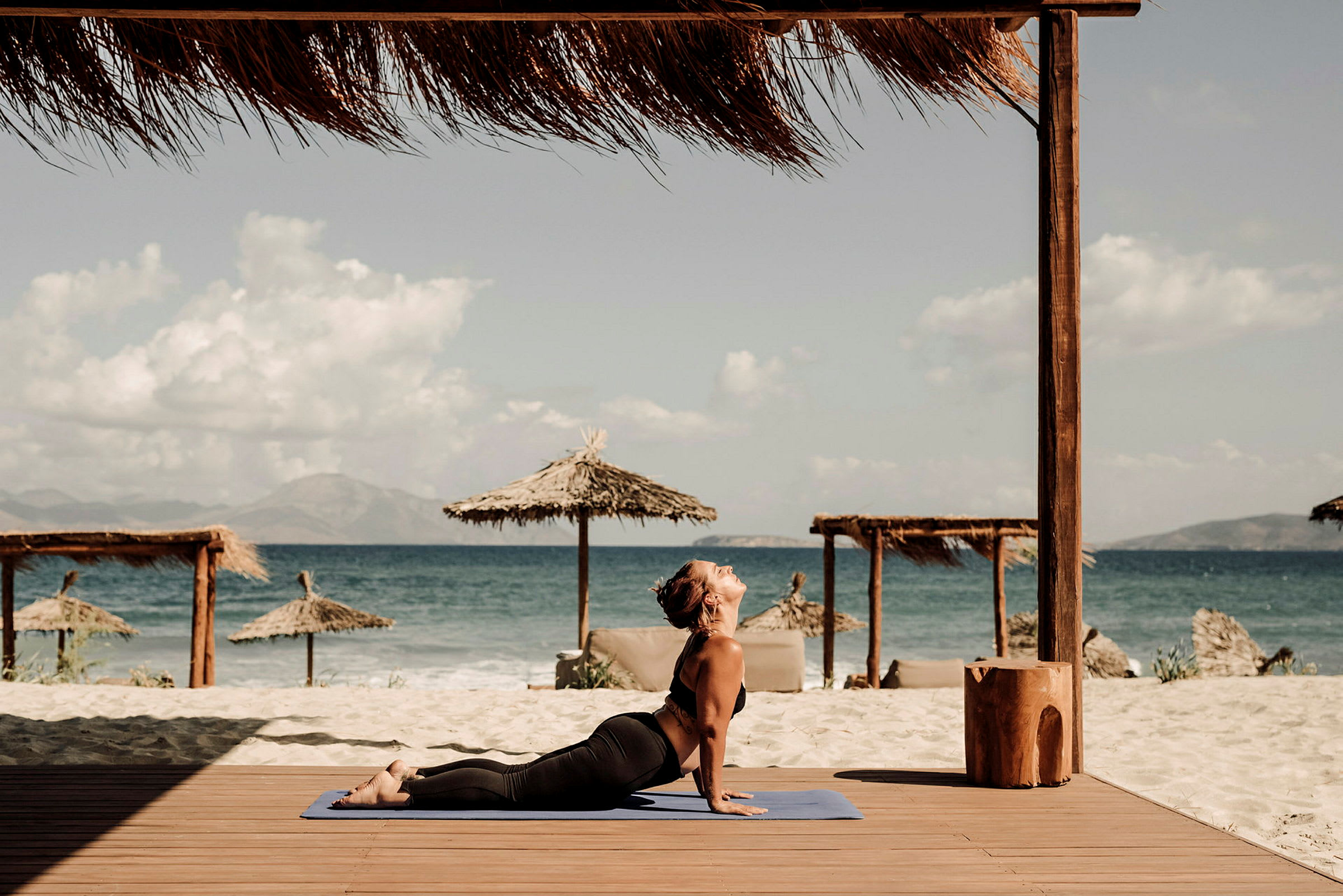 Person på en træplatform ved stranden og havet, laver yoga. (AI-genereret tekst)