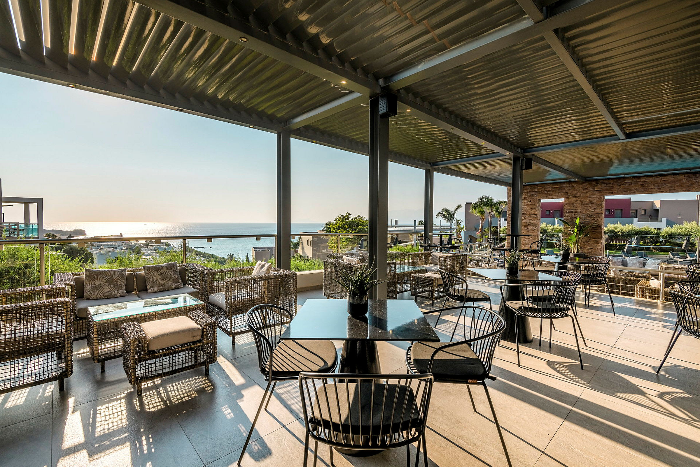 Udendørs terrasse med siddegrupper og udsigt over havet. (AI-genereret tekst)