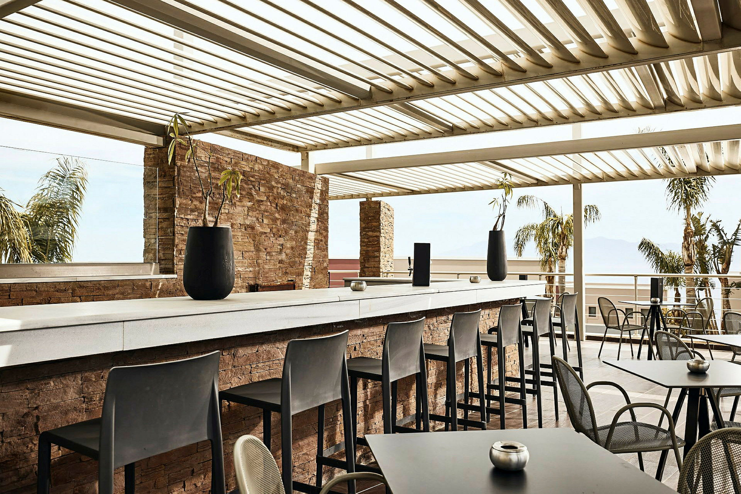 Udendørs serveringsområde med borde, stole og en bar under tag. (AI-genereret tekst)