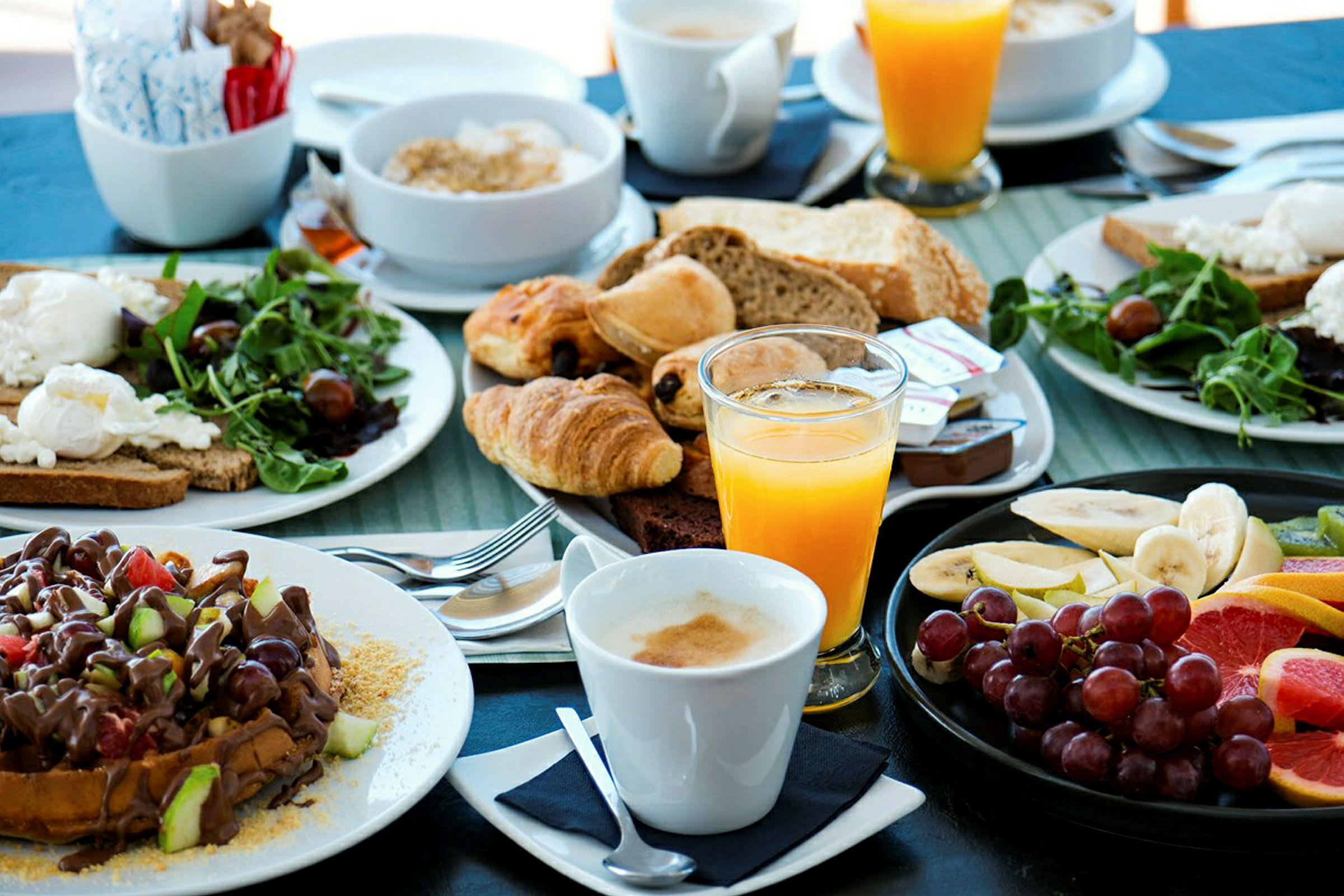 En morgenbuffet med brød, wienerbrød, frugt, salat, appelsinjuice og kaffe. (AI-genereret tekst)