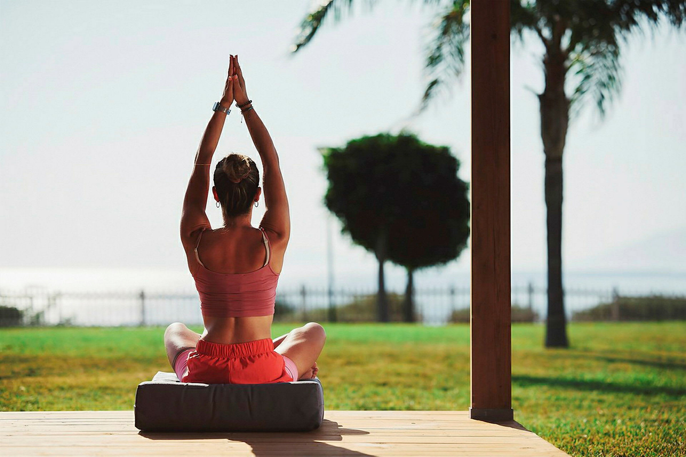 En person laver yoga med hænderne løftet i en siddende position udendørs. (AI-genereret tekst)
