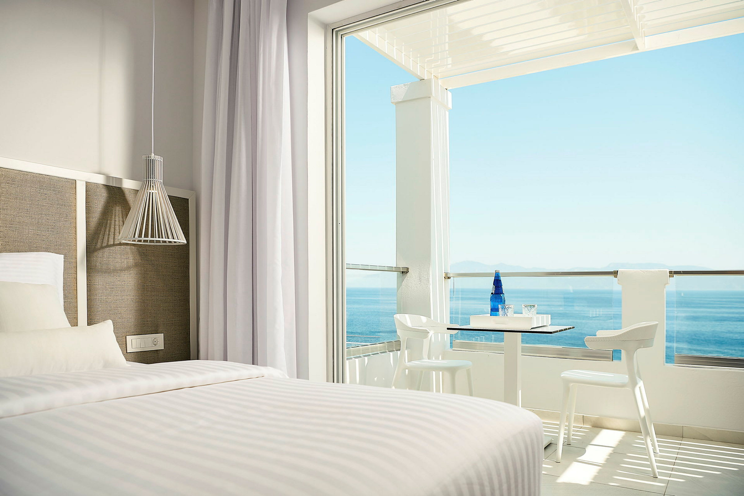 Hotelværelse med seng og terrasse med havudsigt. (AI-genereret tekst)
