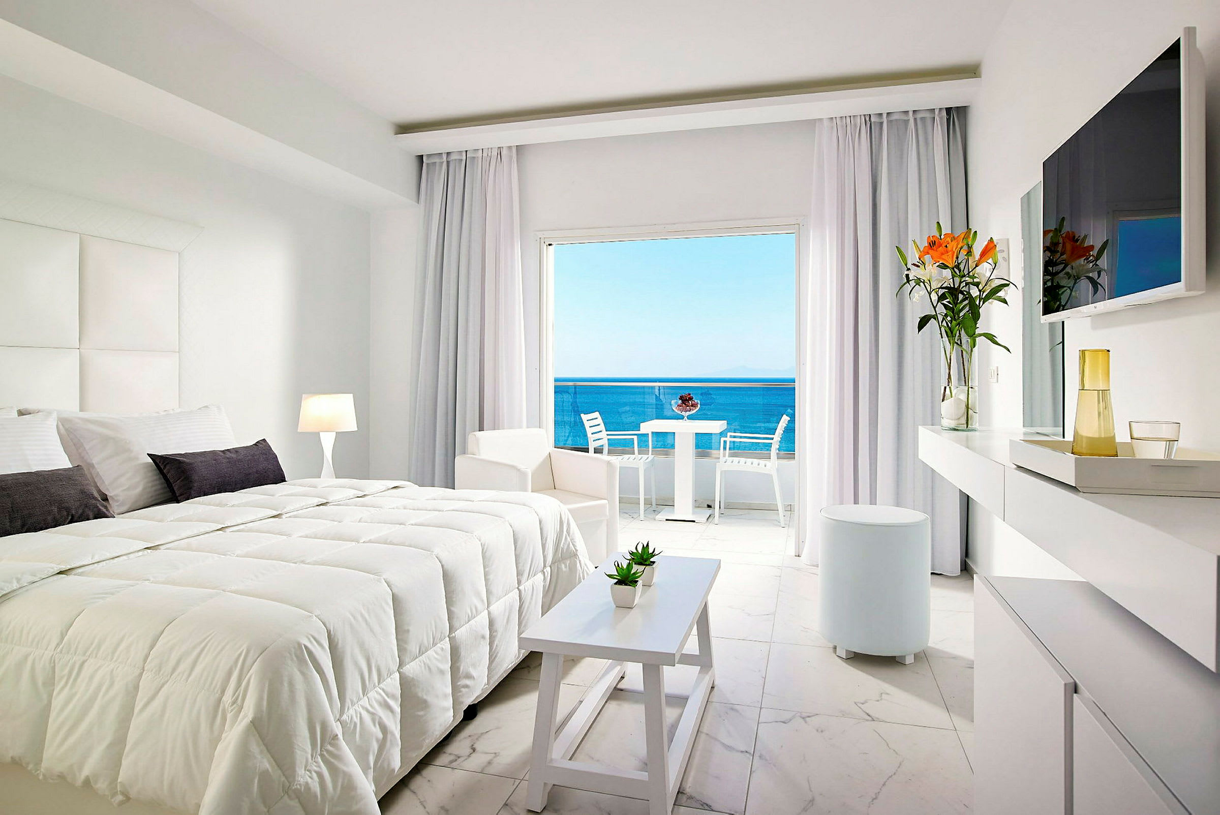 Moderne hotelværelse med dobbeltseng, lyse møbler og udsigt over havet. (AI-genereret tekst)