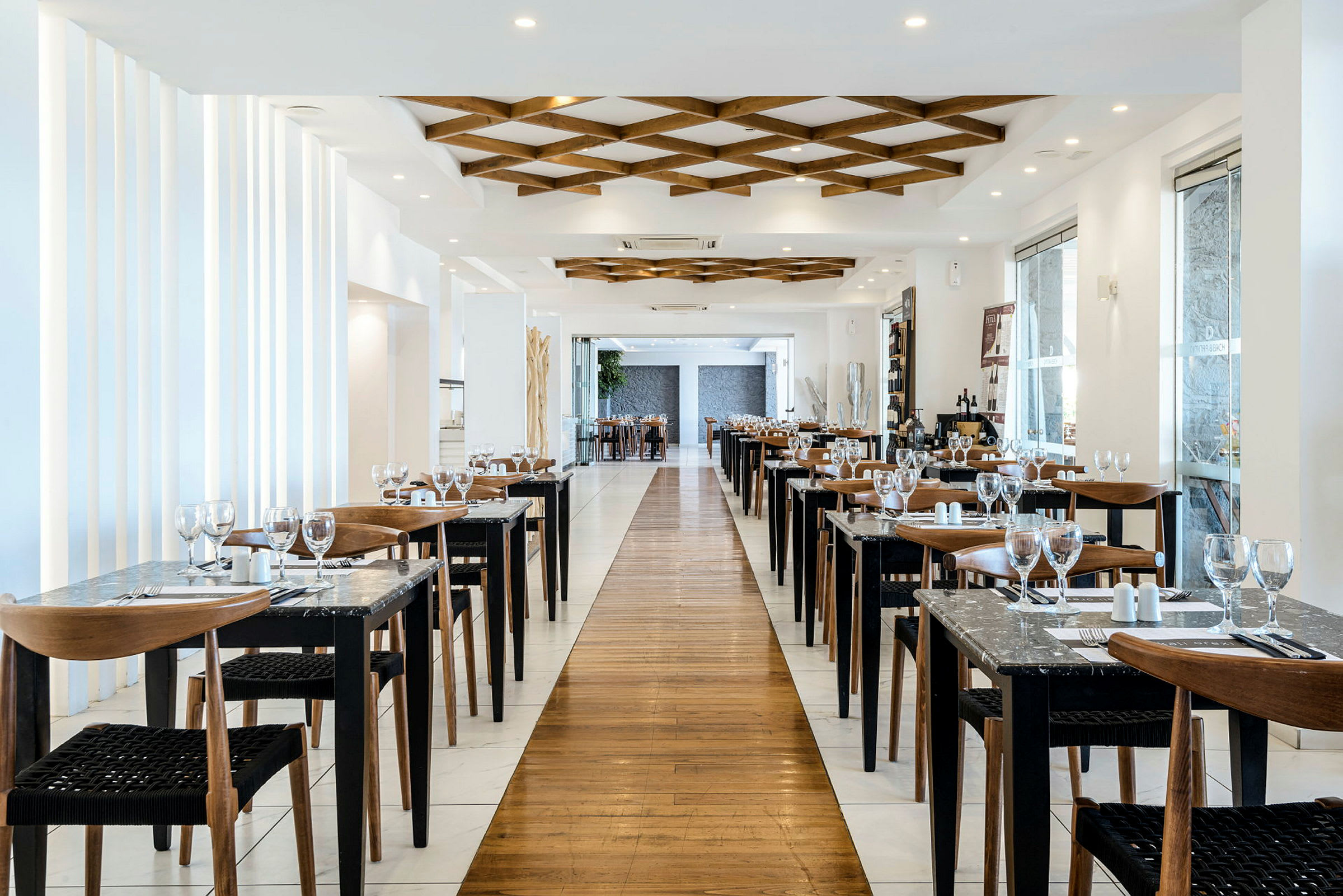 En elegant restaurant med opstillet borde og stole langs begge sider af en gang, dekoreret med moderne interiør. (AI-genereret tekst)
