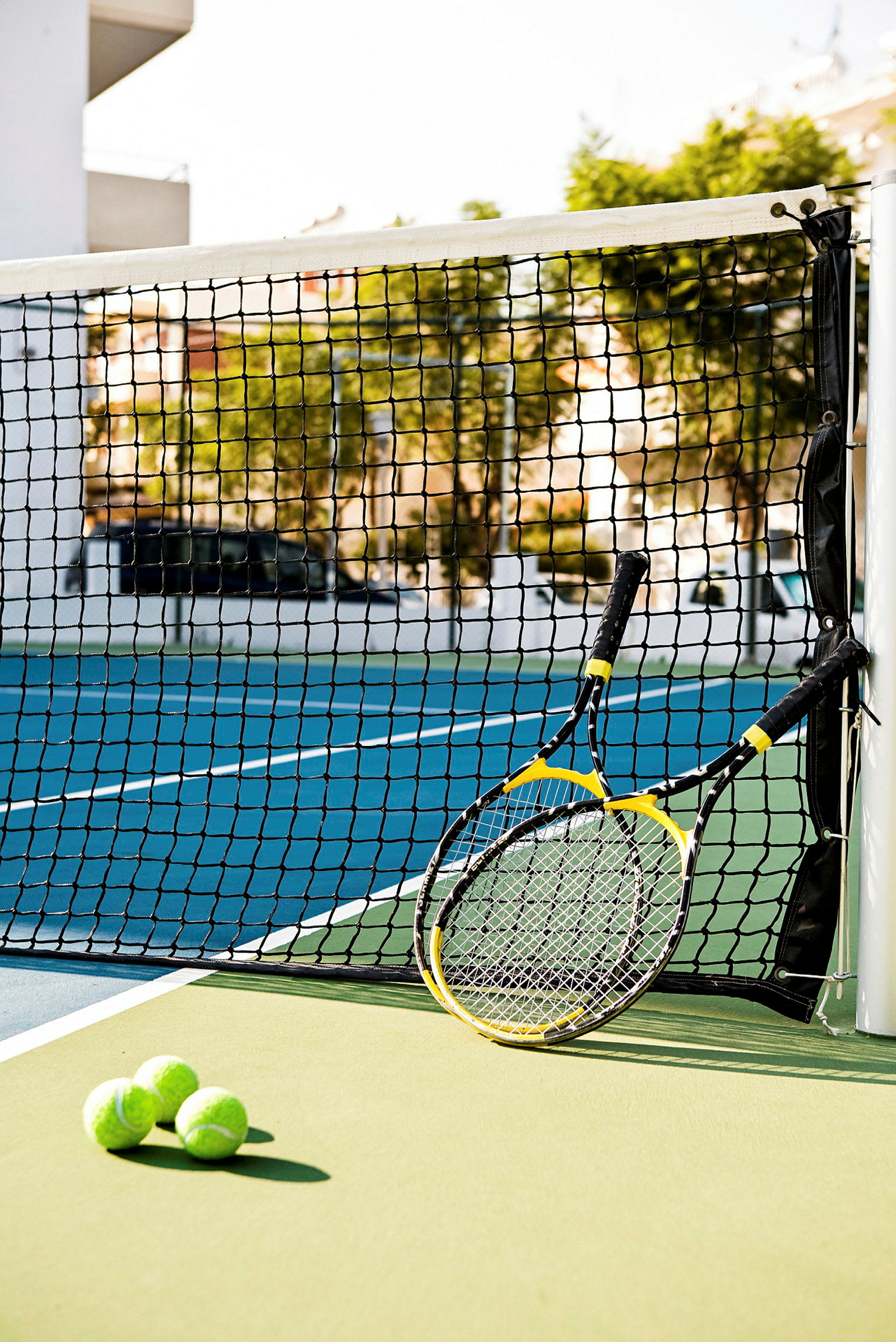 To tennisrackets og tre tennisbolde ved et net på en tennisbane. (AI-genereret tekst)