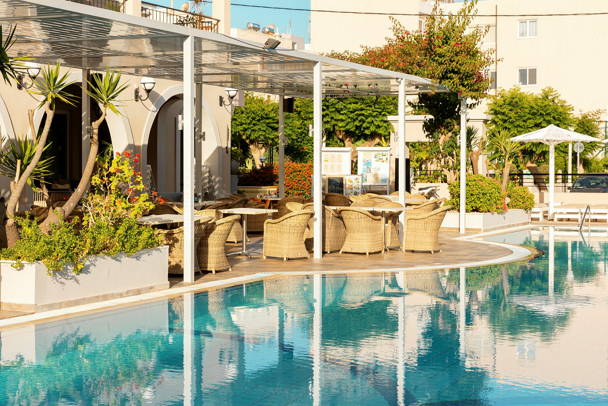 Hotelpool med siddeområder og planter i baggrunden. (AI-genereret tekst)