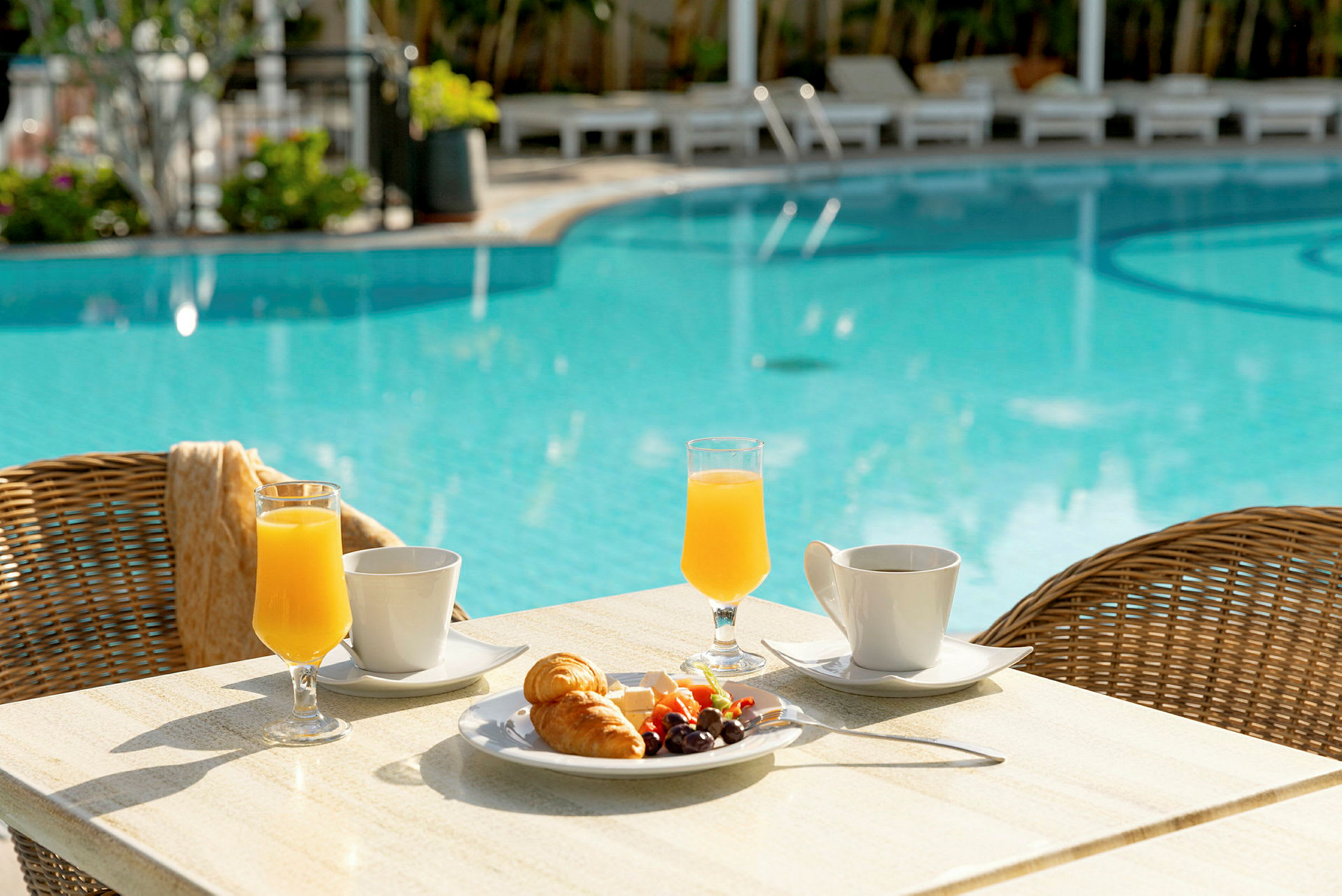 Et bord med morgenmad ved en pool. (AI-genereret tekst)