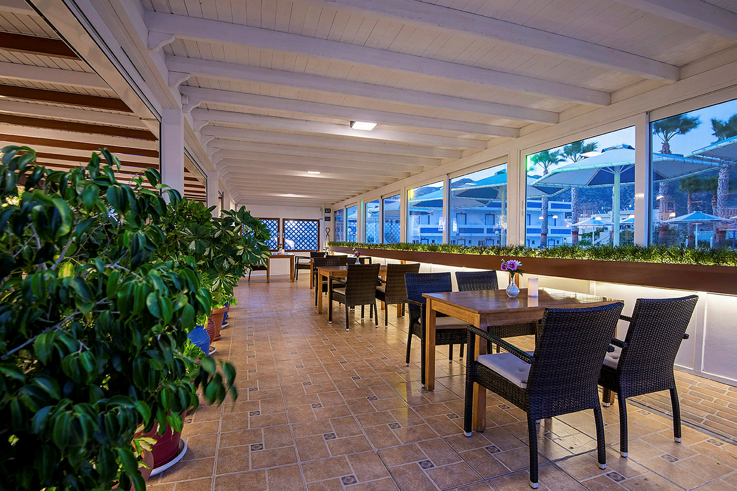 En rummelig terrasse med borde og stole samt planteudsmykning. (AI-genereret tekst)