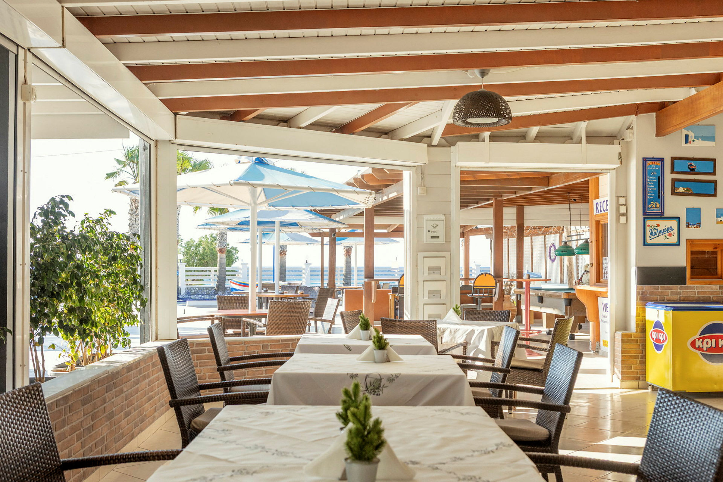 Restaurant med borde og stole, udendørsområde med parasoller ses i baggrunden. (AI-genereret tekst)