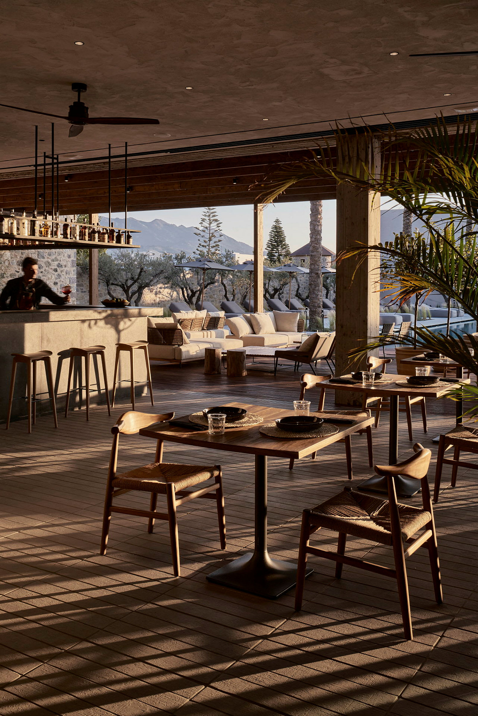 En elegant restaurant med udsigt over et udendørsområde og bjerge i baggrunden. (AI-genereret tekst)