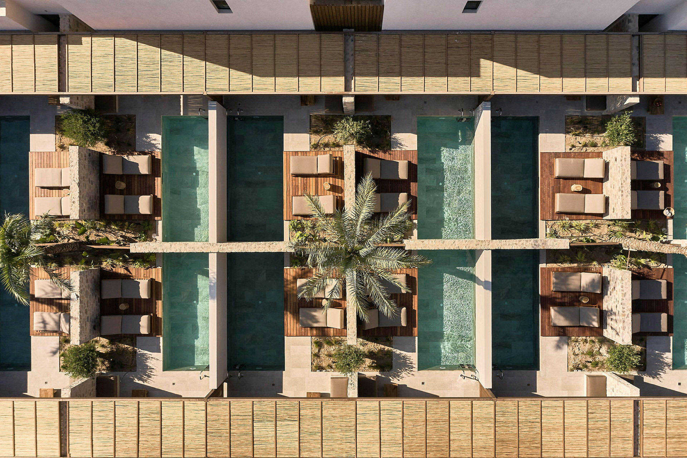 Luftfoto af et hotelområde med private swimmingpools og solsenge. (AI-genereret tekst)