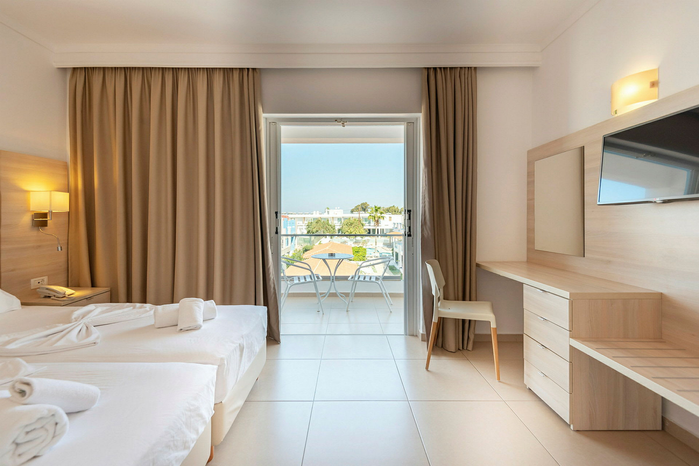 Et hotelværelse med to senge, skrivebord og balkon. (AI-genereret tekst)