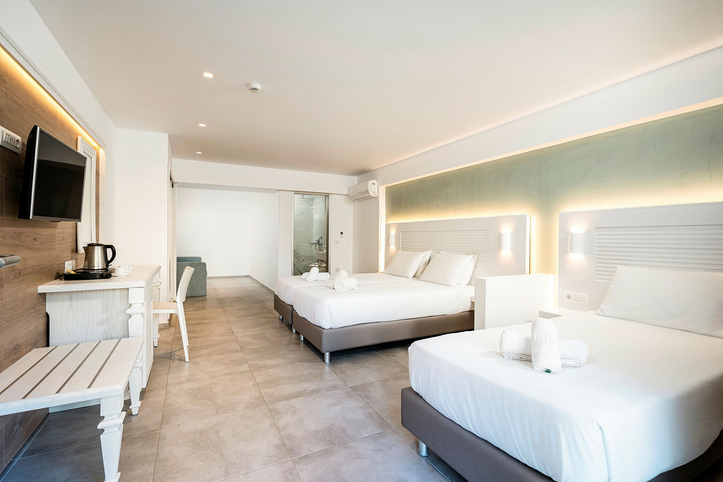 Moderne hotelværelse med to dobbeltsenge, møbler og udsigt til badeværelset. (AI-genereret tekst)
