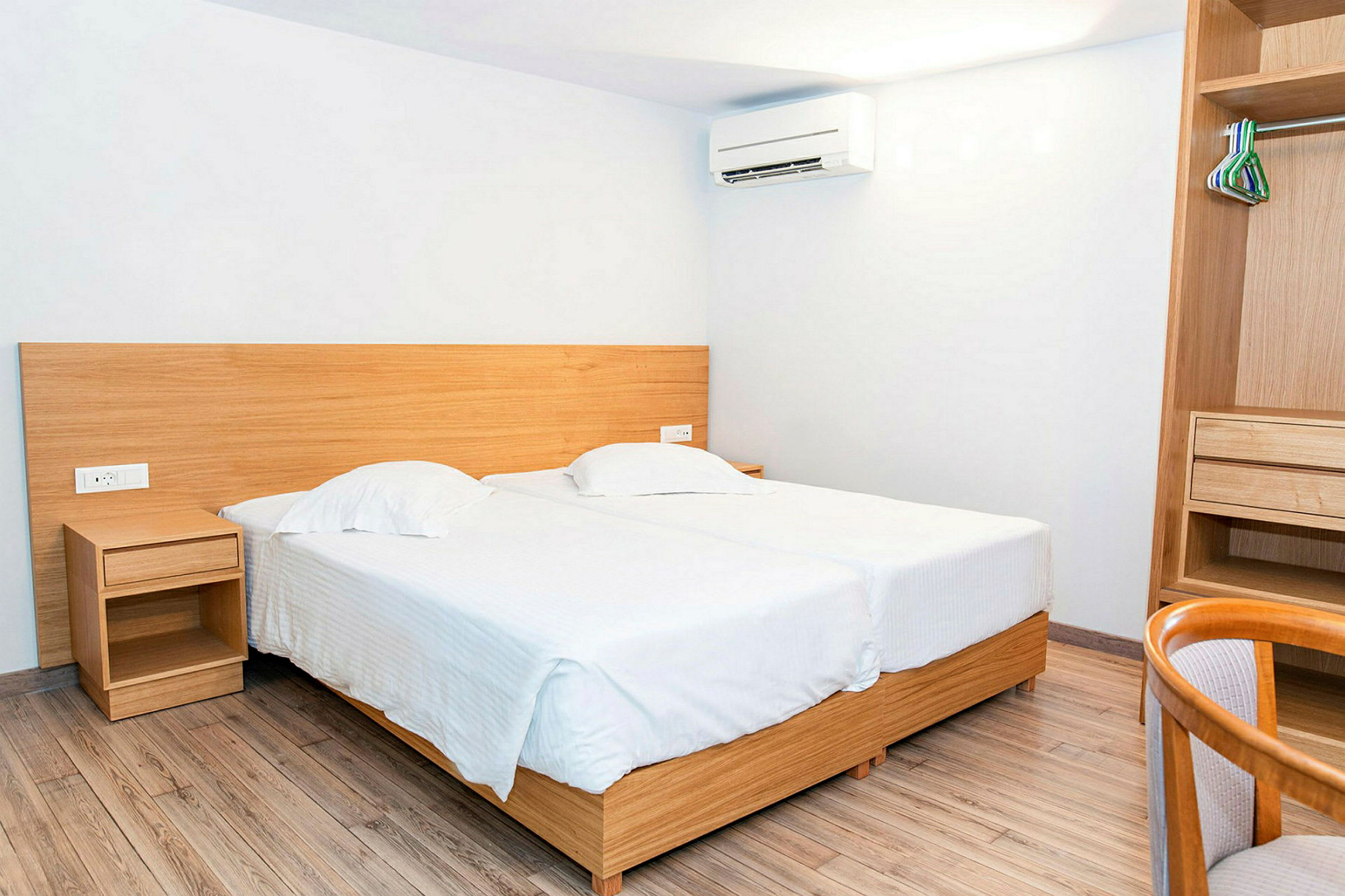 Indretning af et hotelværelse med to enkeltsenge og en åben garderobe. (AI-genereret tekst)