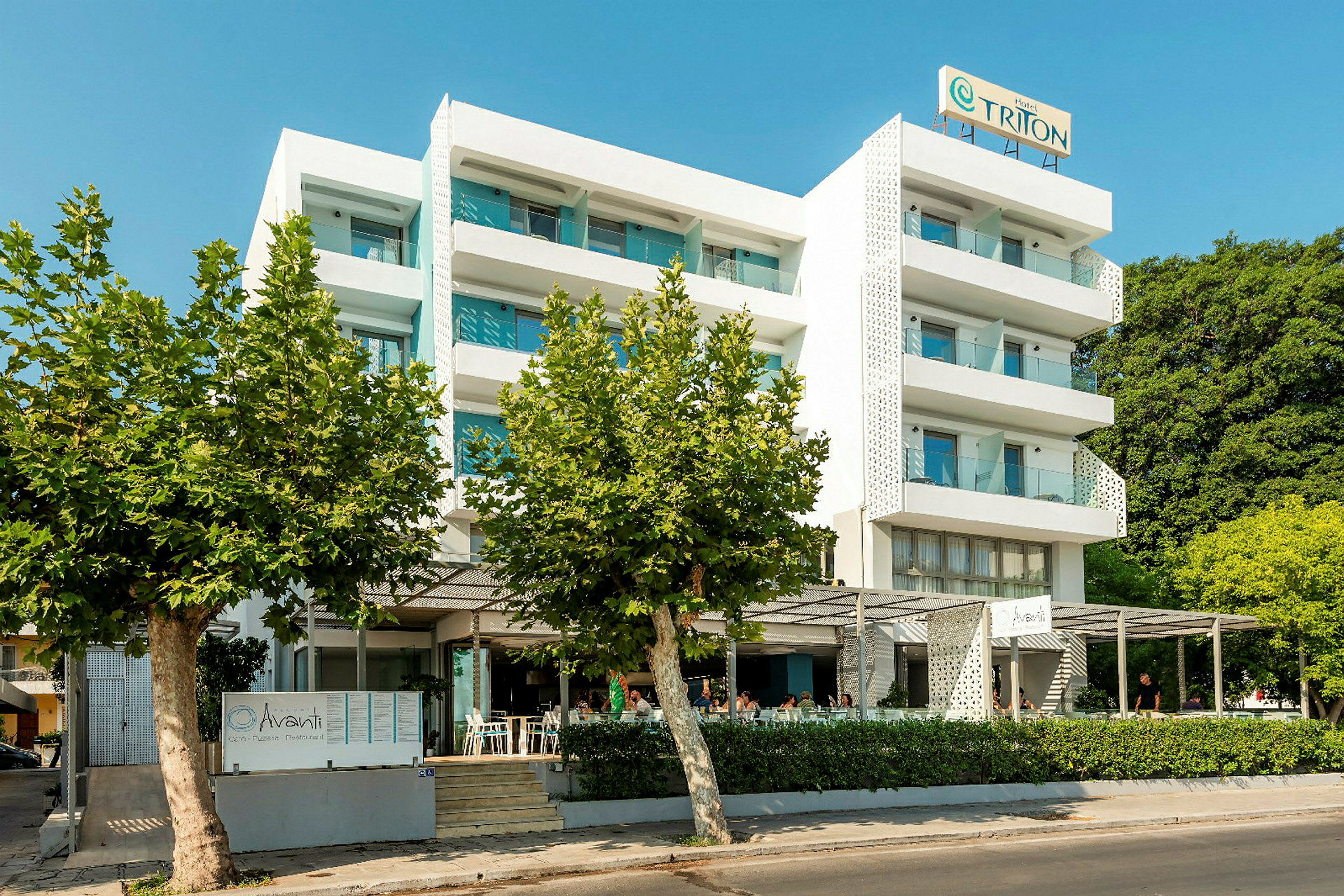 Flereetagers hotel med hvide facader, altaner og restaurant foran bygningen. (AI-genereret tekst)