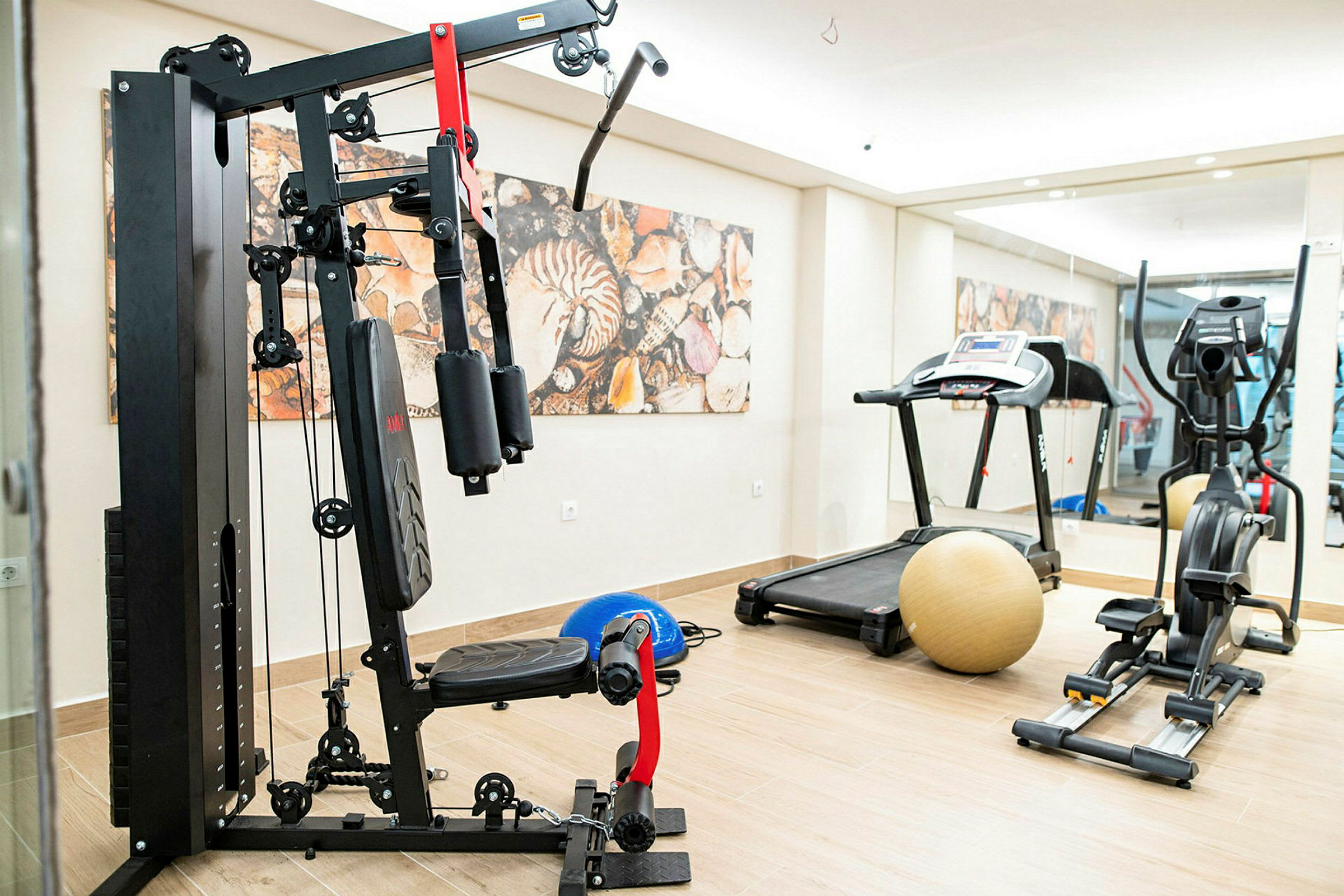 Billede af et fitnesscenter med træningsudstyr, herunder en vægtmaskine, et løbebånd og en motionscykel. (AI-genereret tekst)
