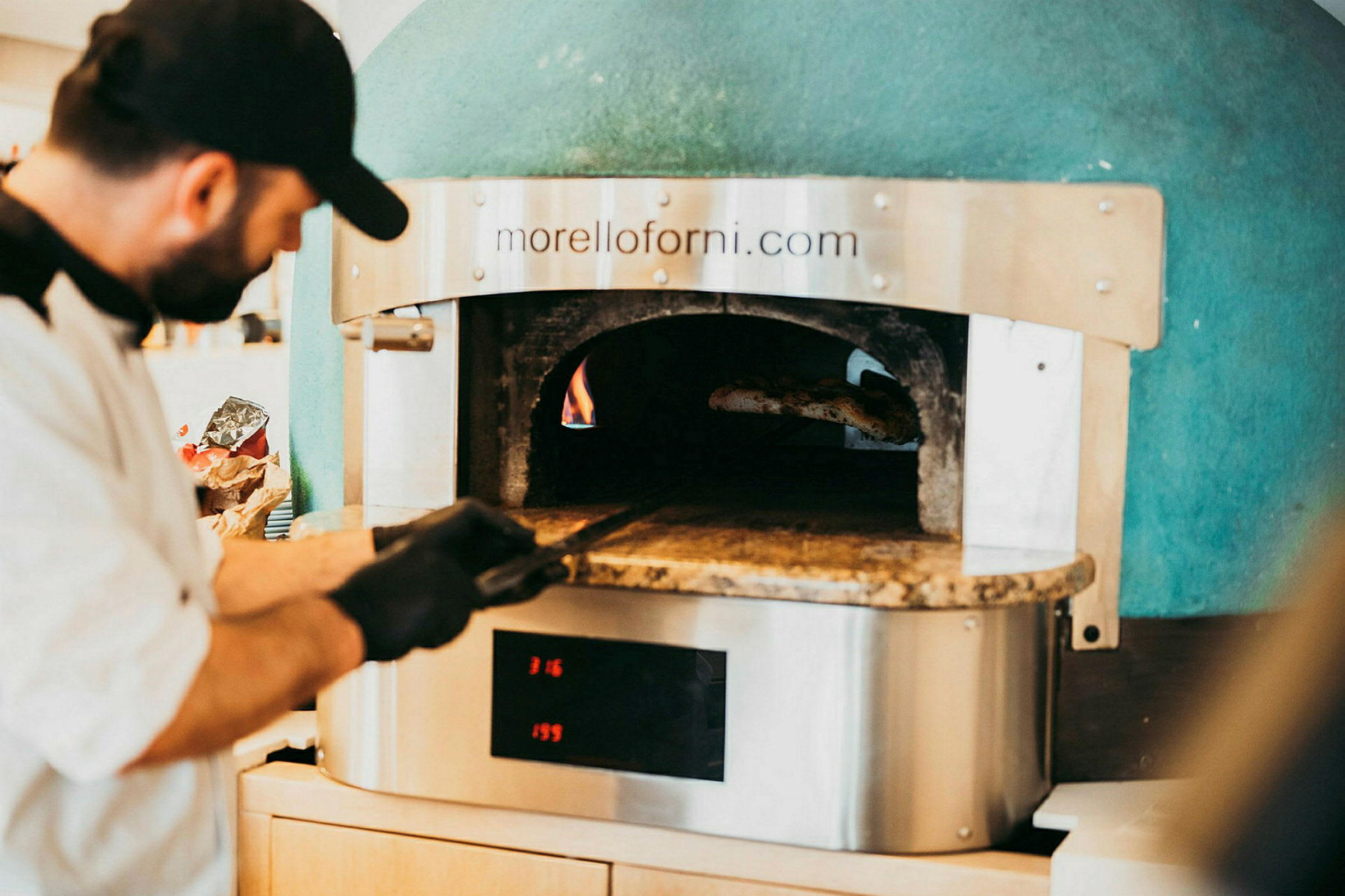 En brændefyret ovn med ild og pizzaspade. (AI-genereret tekst)