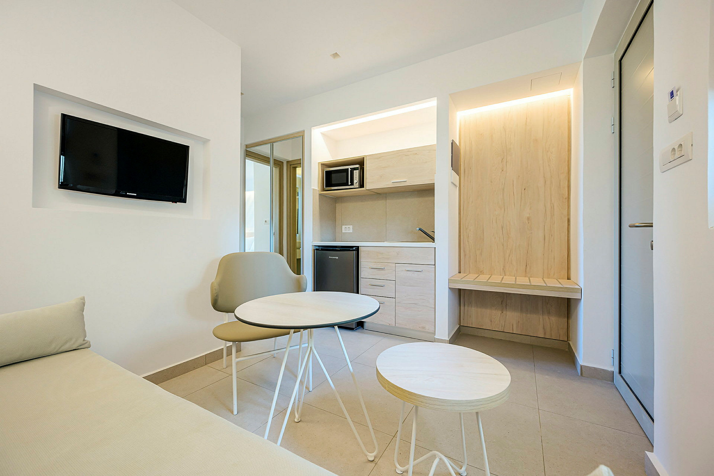 Et moderne hotelværelse med en lille siddegruppe og køkkenområde. (AI-genereret tekst)
