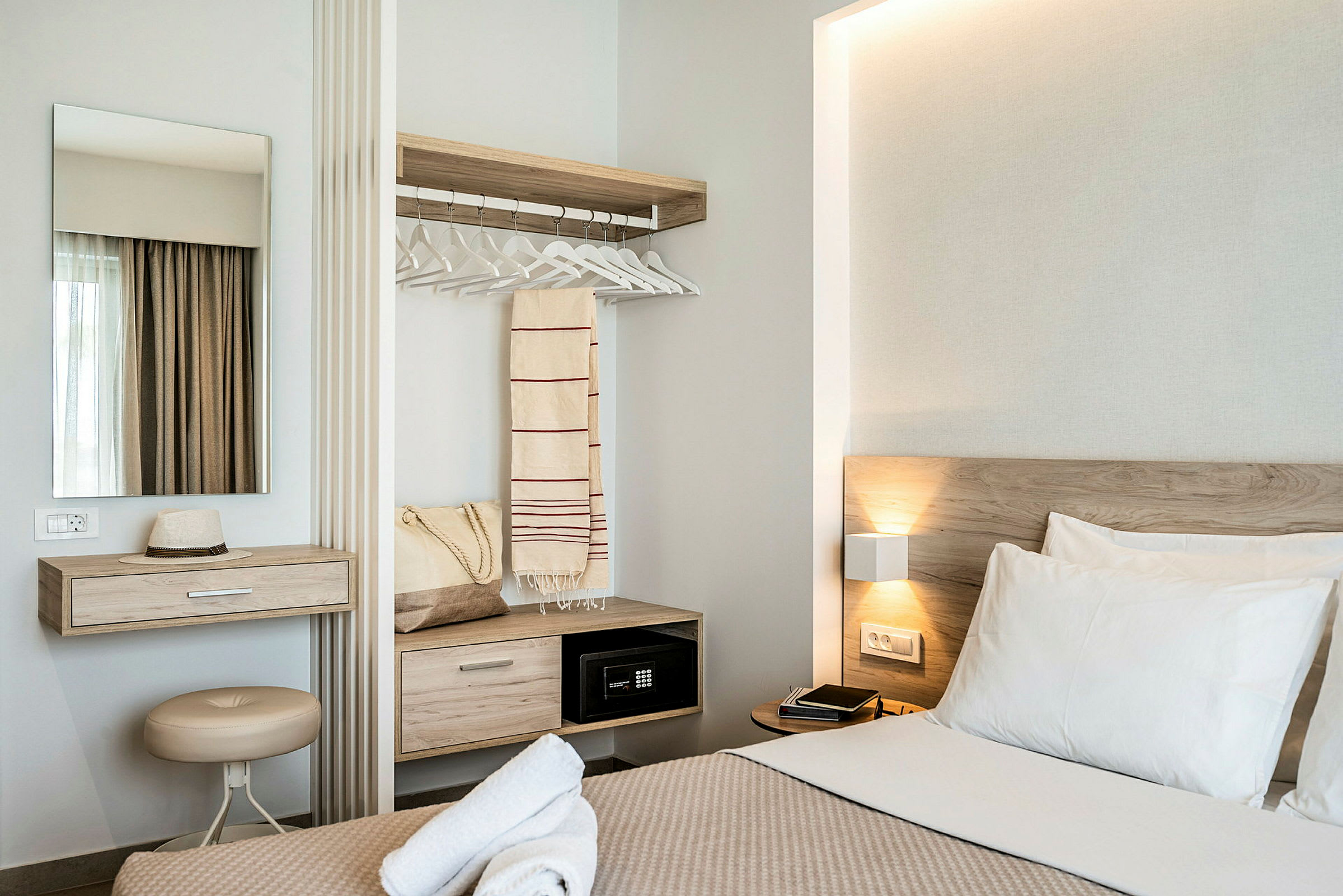 Moderne hotelværelse med seng, skrivebord, spejl og garderobe. (AI-genereret tekst)