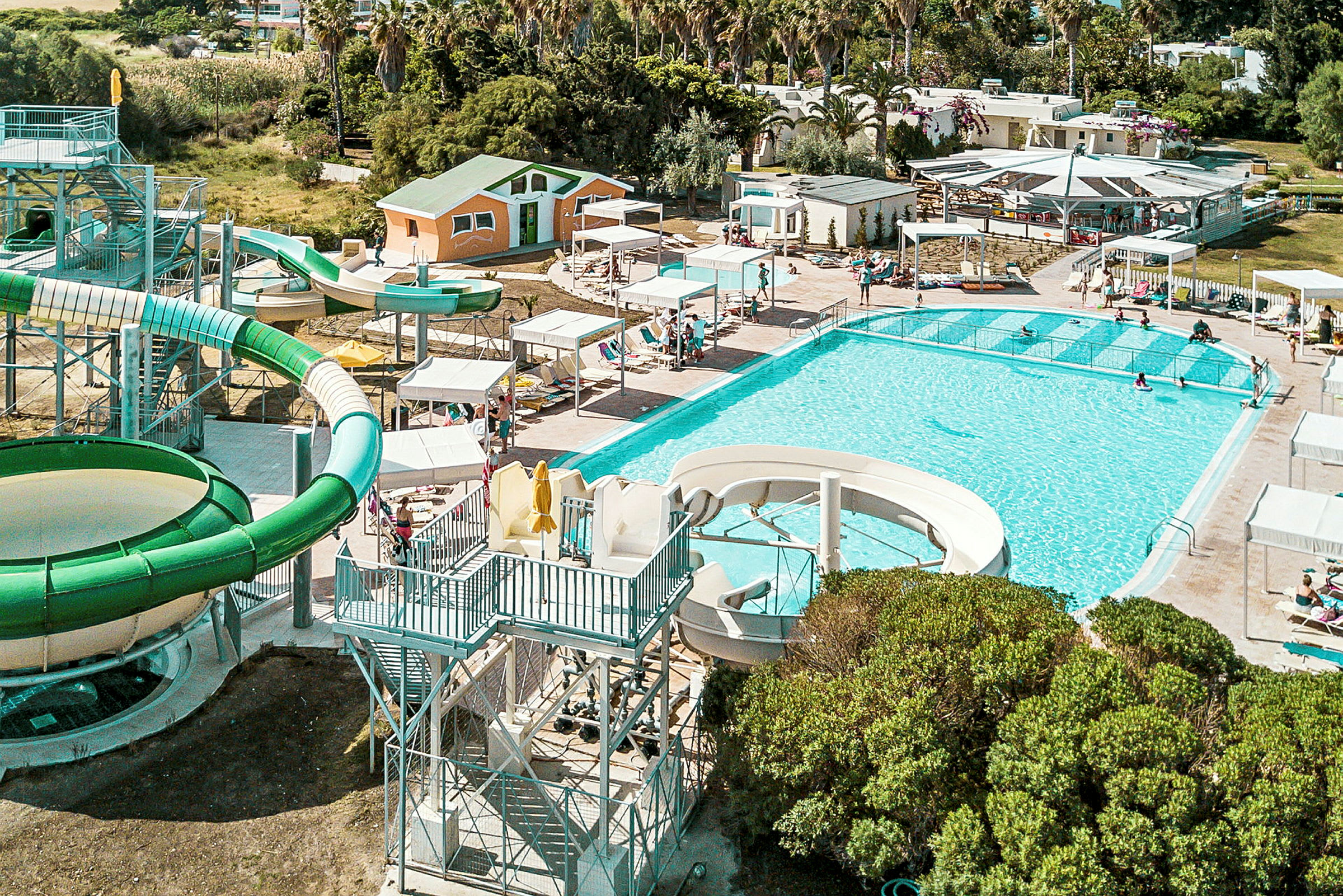 Udendørs swimmingpool med liggestole og vandrutsjebaner. (AI-genereret tekst)