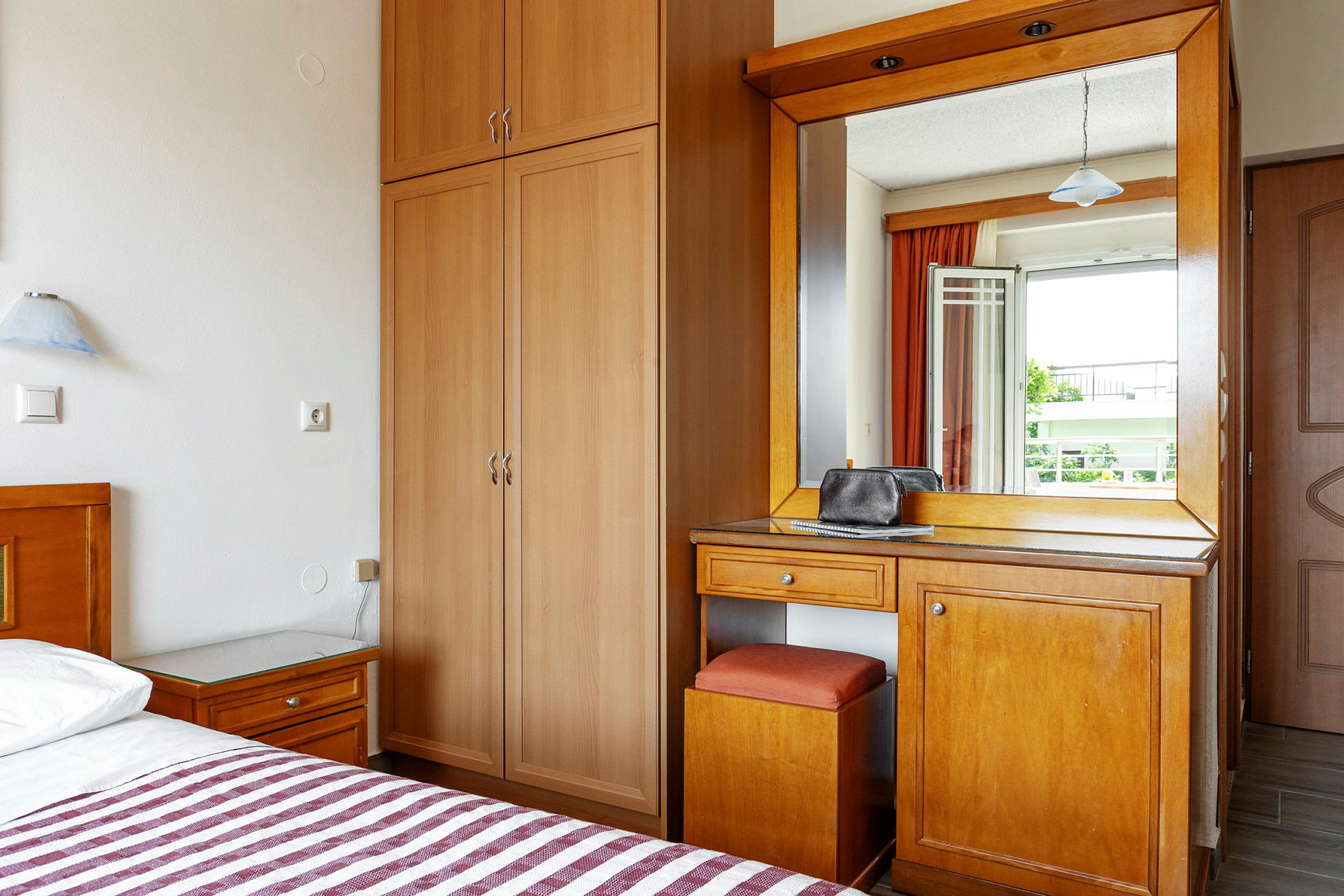 Hotelværelse med garderobe, skrivebord og spejl. (AI-genereret tekst)
