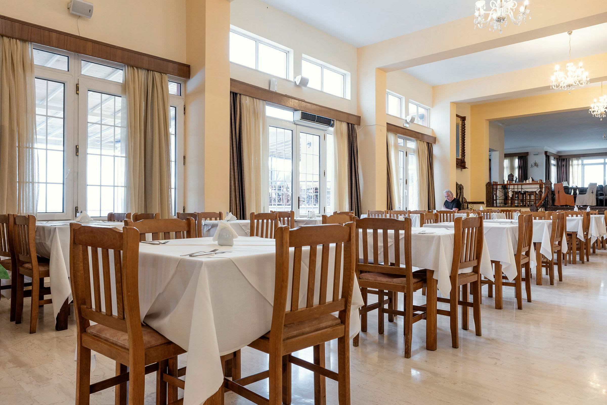 Restaurant med borde dækket med hvide duge og træstole. (AI-genereret tekst)