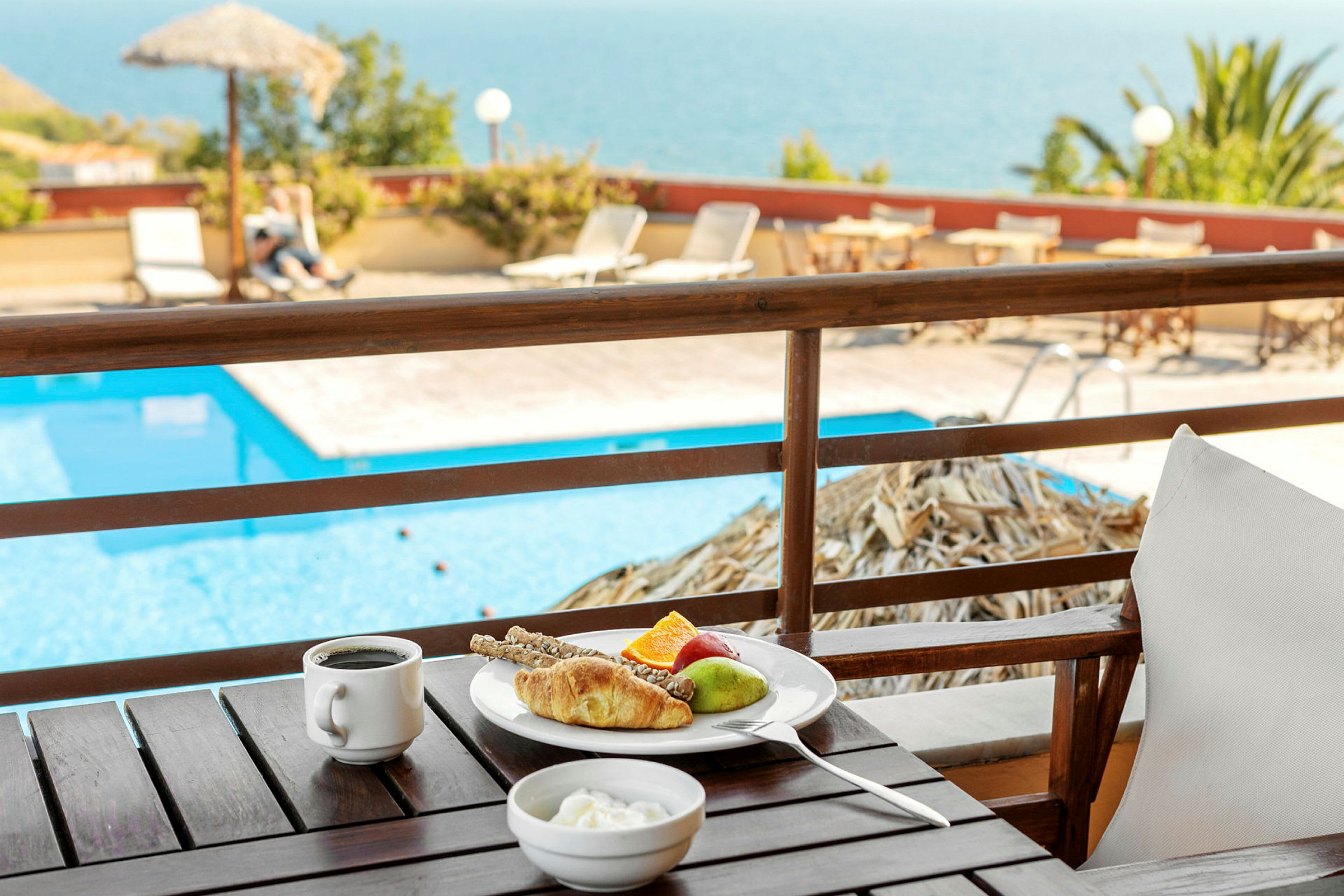 En tallerken med morgenmad på et bord med udsigt over en pool. (AI-genereret tekst)