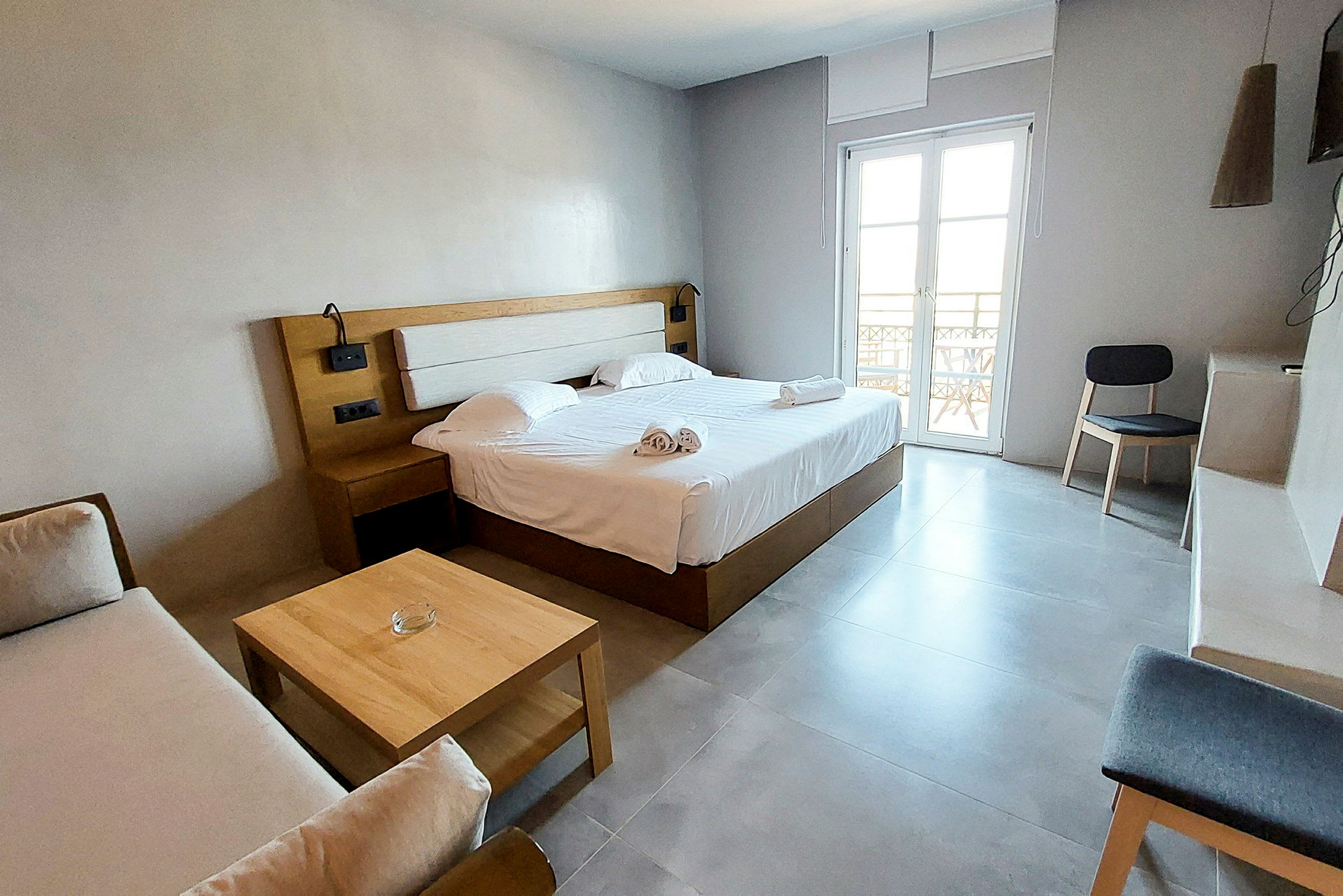 Moderne hotelværelse med dobbeltseng, sofa og trædetaljer. (AI-genereret tekst)