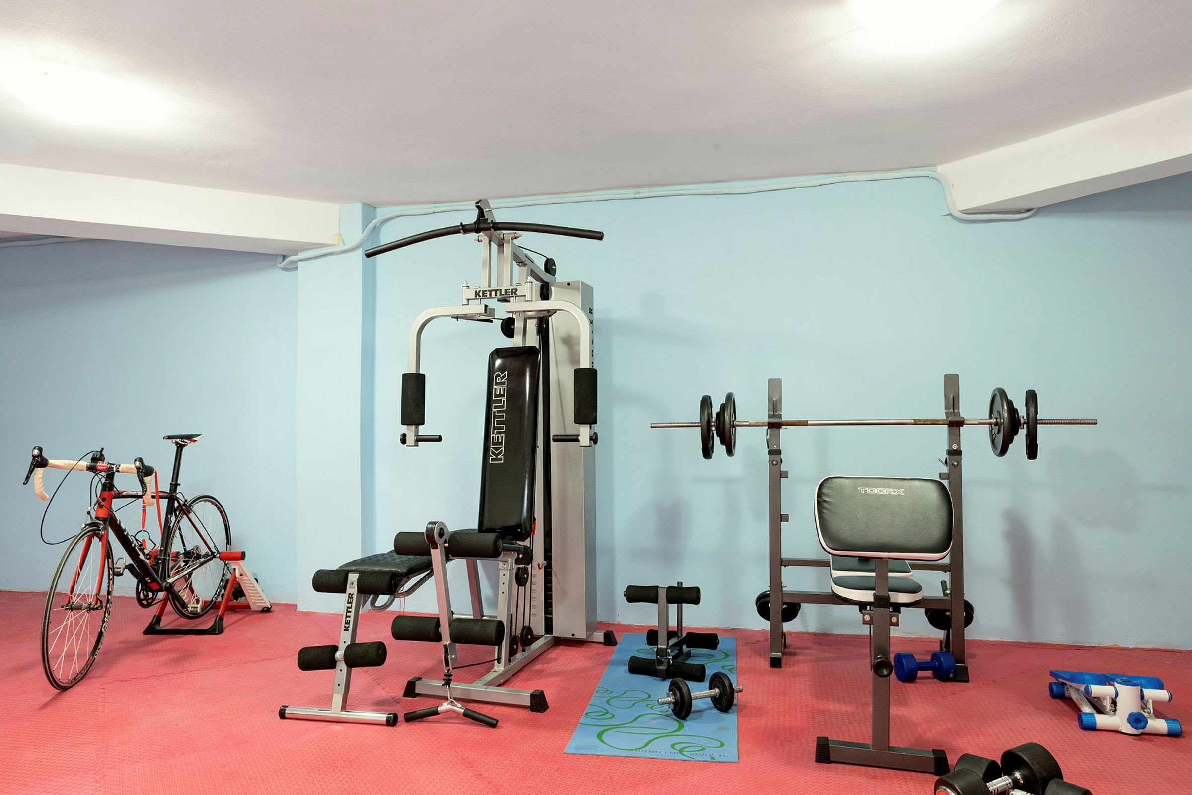 Et fitnessrum med træningsudstyr, herunder en motionscykel, styrketræningsmaskiner og forskellige vægte. (AI-genereret tekst)