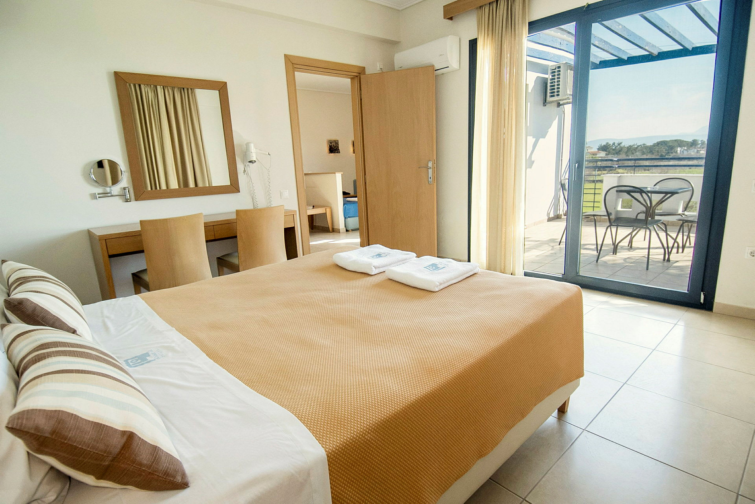 Billedet viser et hotelværelse med en seng, et skrivebord og en balkon med udsigt. (AI-genereret tekst)