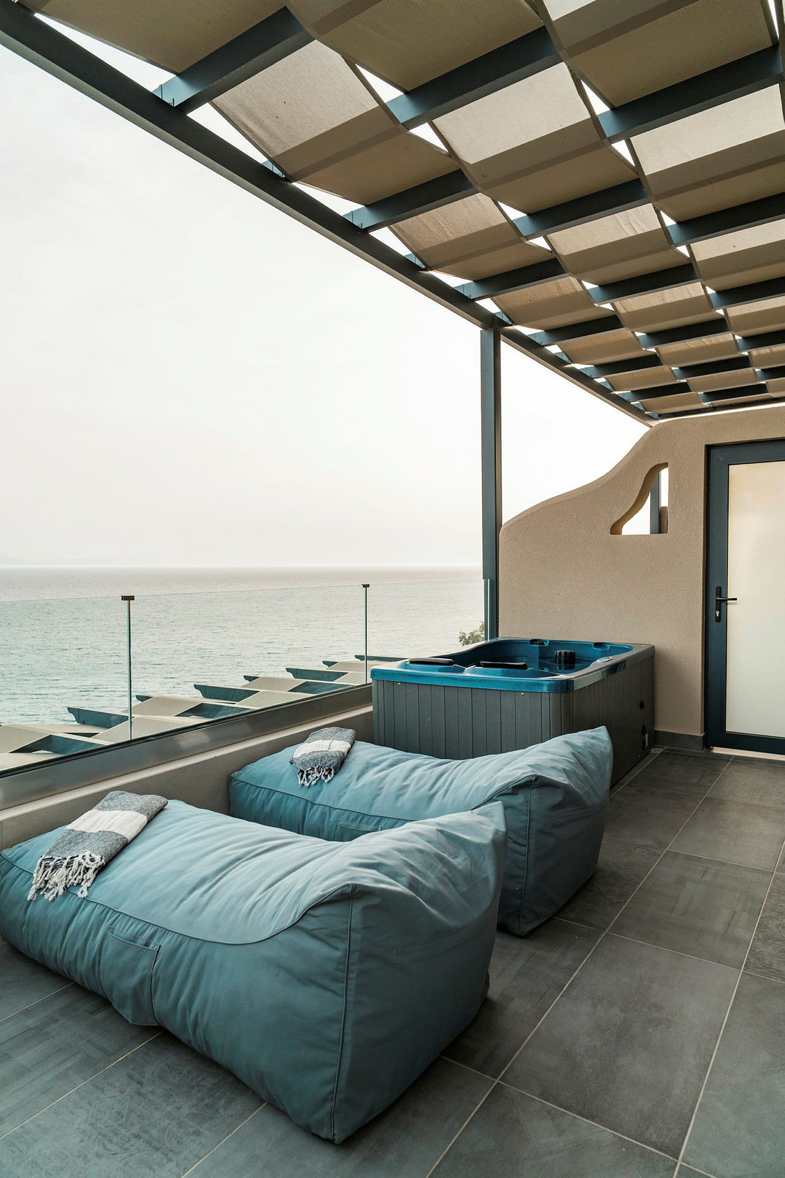 Terrasse med siddepladser og jacuzzi samt udsigt til havet. (AI-genereret tekst)