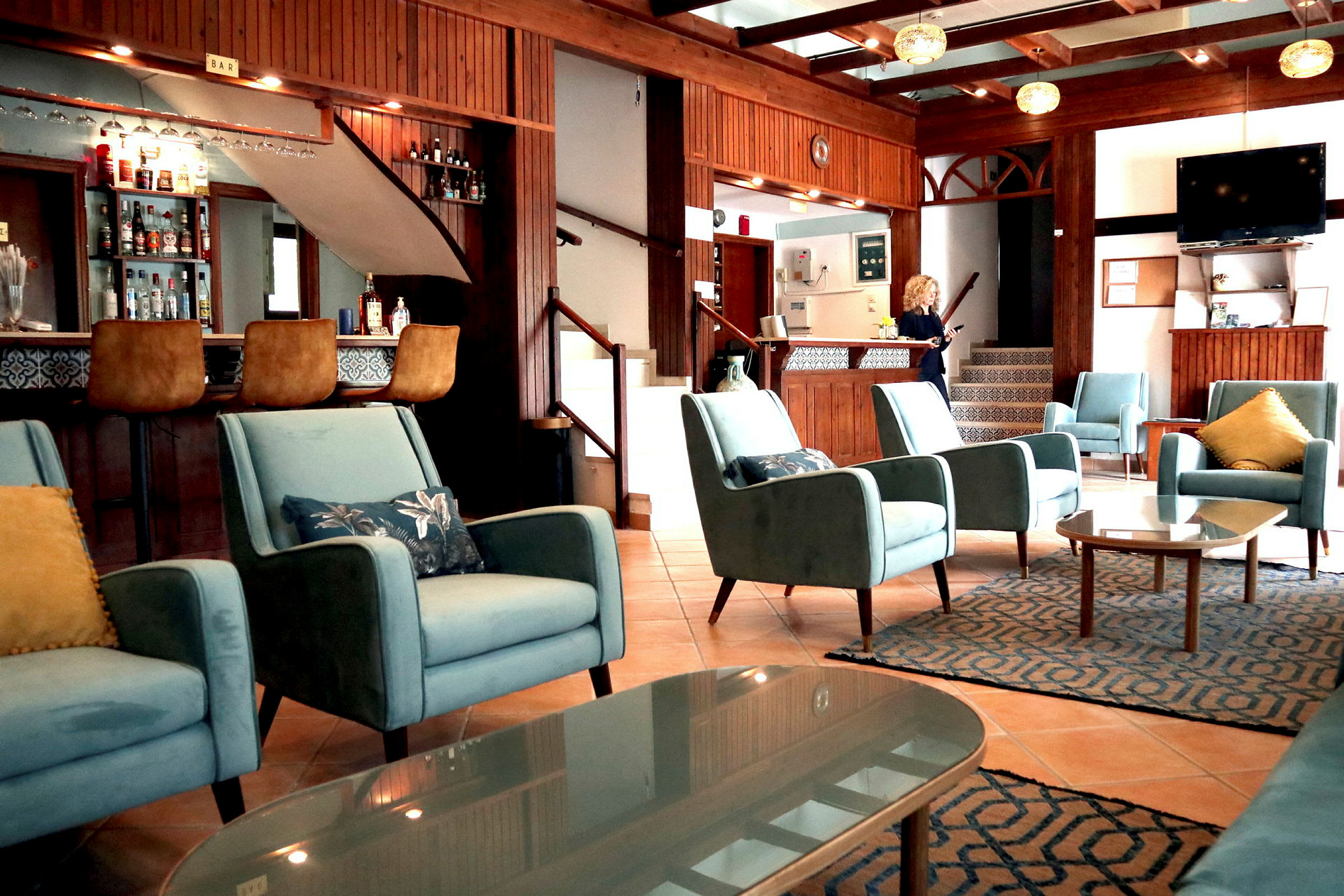 Interiør af et hotel med blå stole, bar og reception. (AI-genereret tekst)
