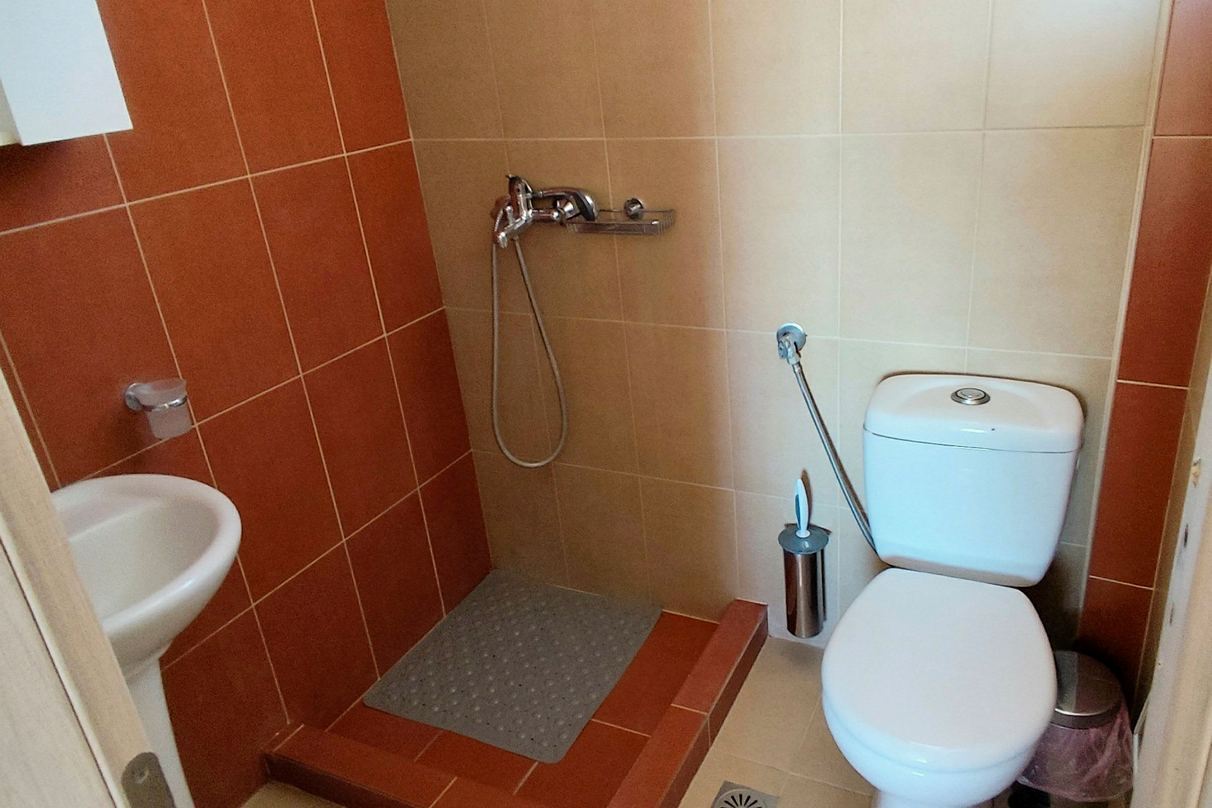 Et badeværelse med bruser, toilet og håndvask. (AI-genereret tekst)
