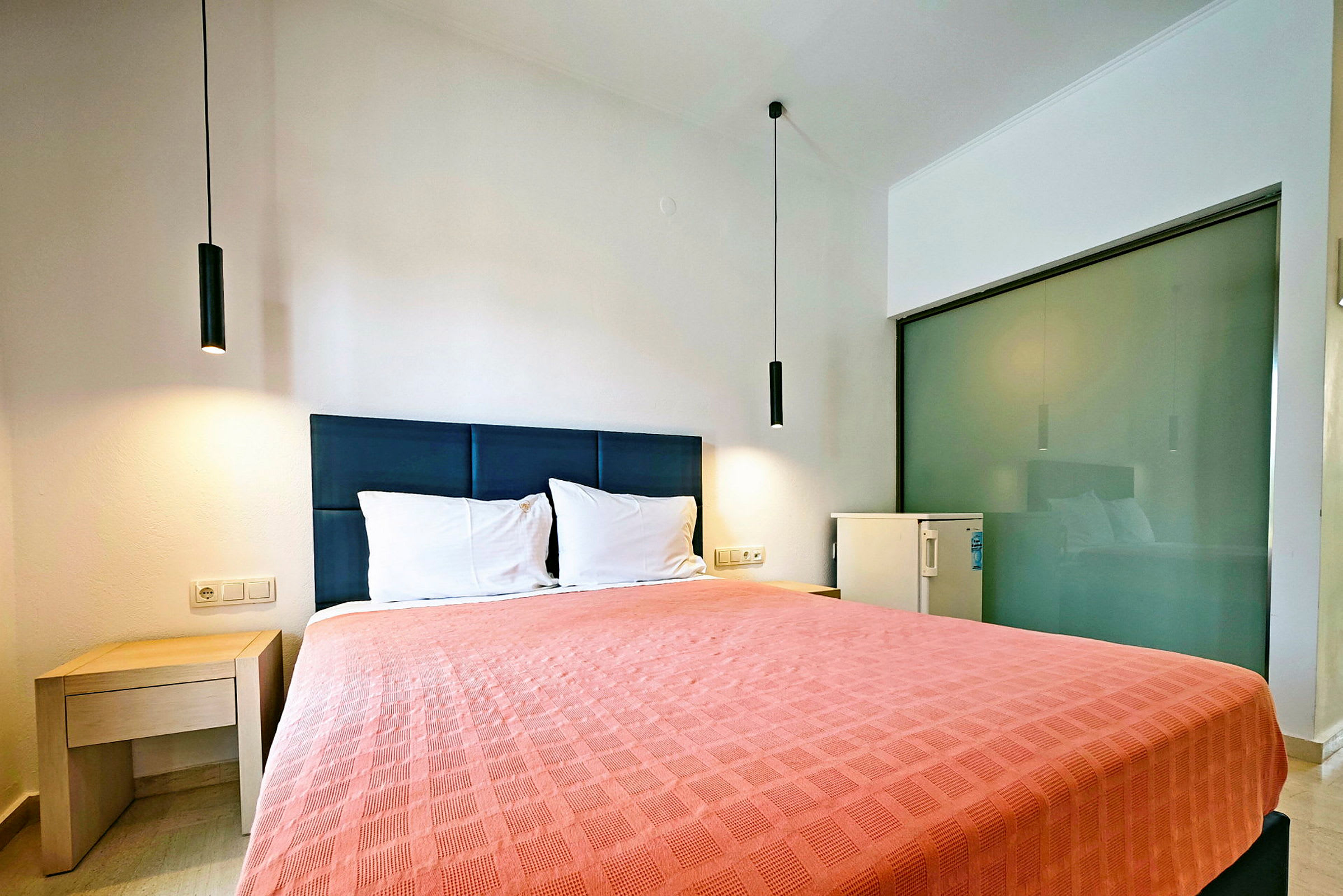 Hotelværelse med en dobbeltseng og enkel indretning. (AI-genereret tekst)