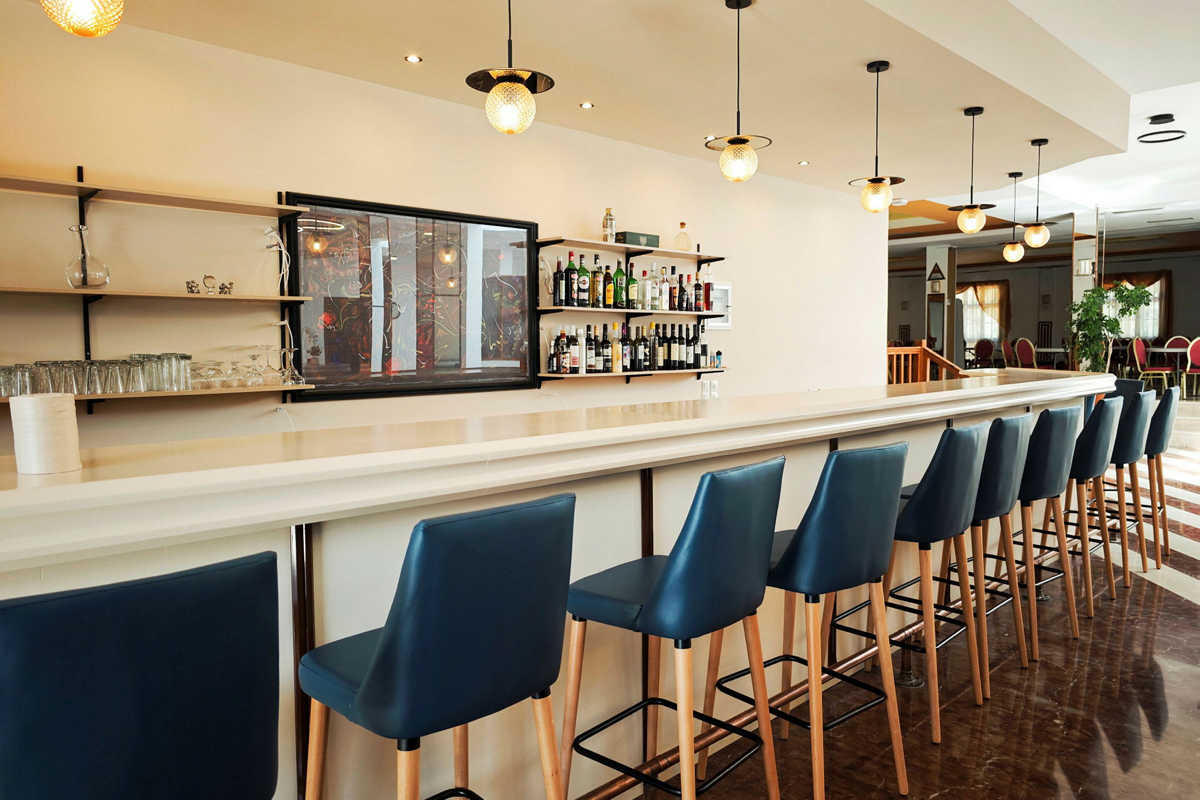 En lys hotelbar med blå barstole. (AI-genereret tekst)