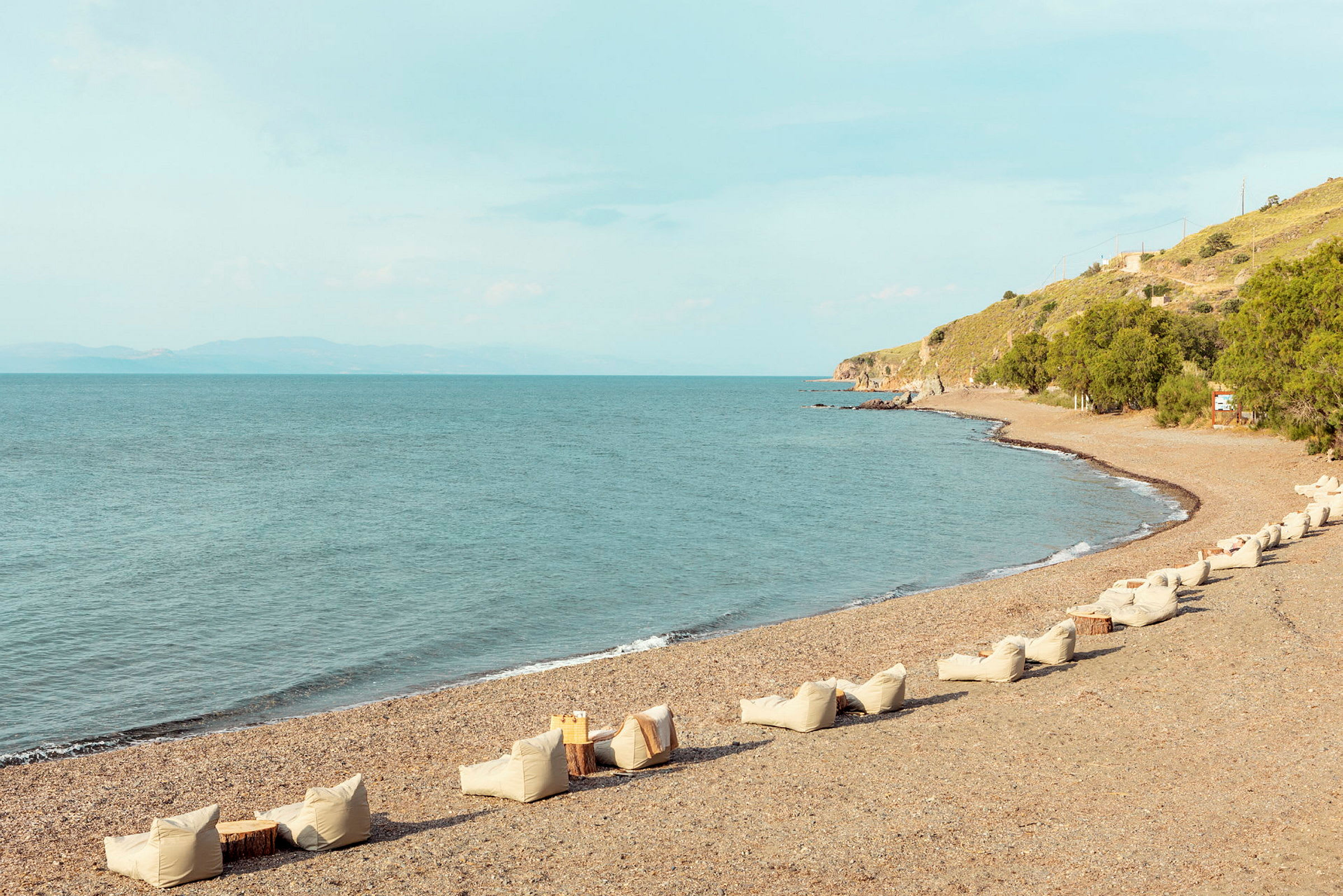 Billede af en stenstrand med havet i baggrunden og sæder på stranden. (AI-genereret tekst)