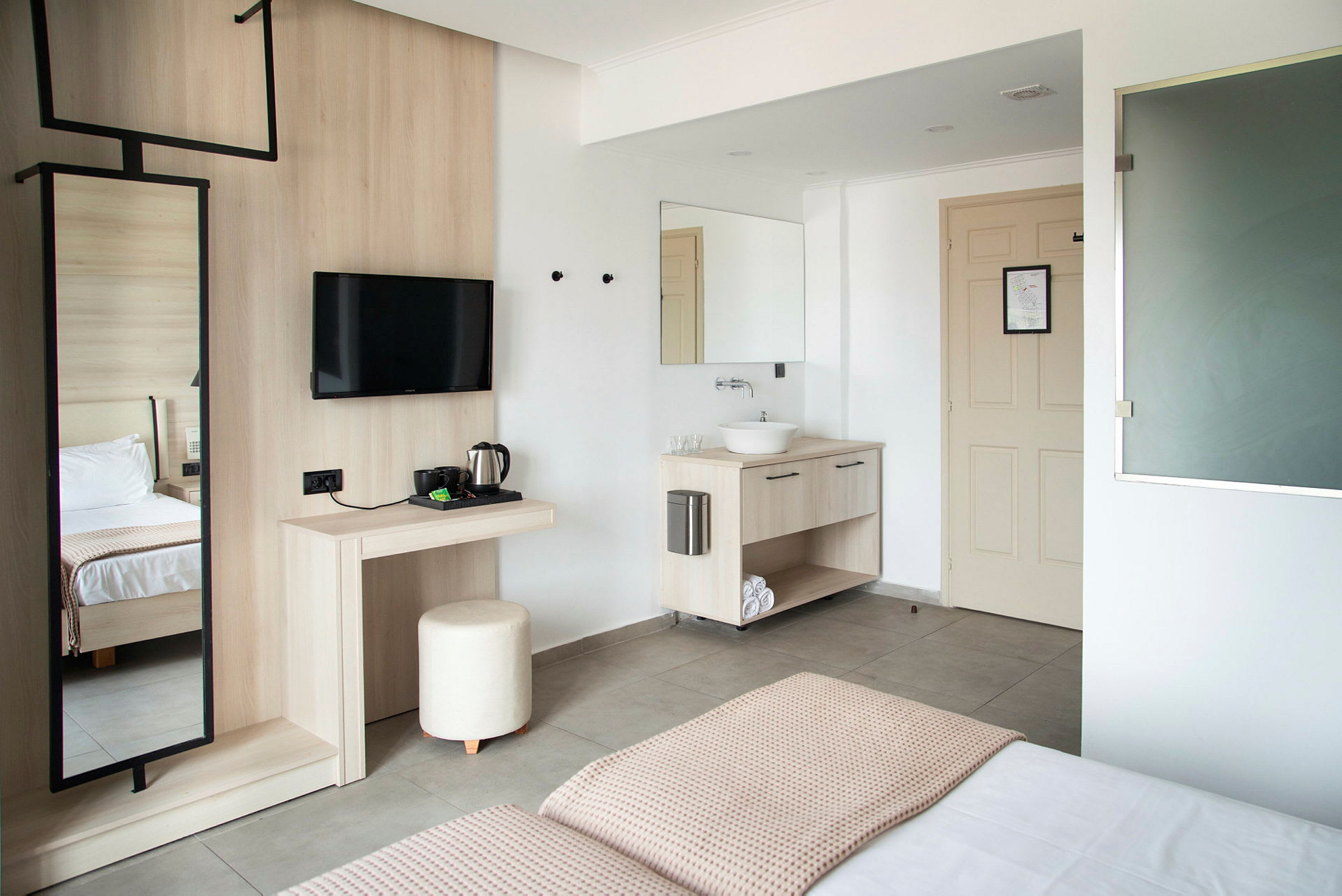Moderne indrettet hotelværelse med bord, spejl, TV, seng og håndvask. (AI-genereret tekst)