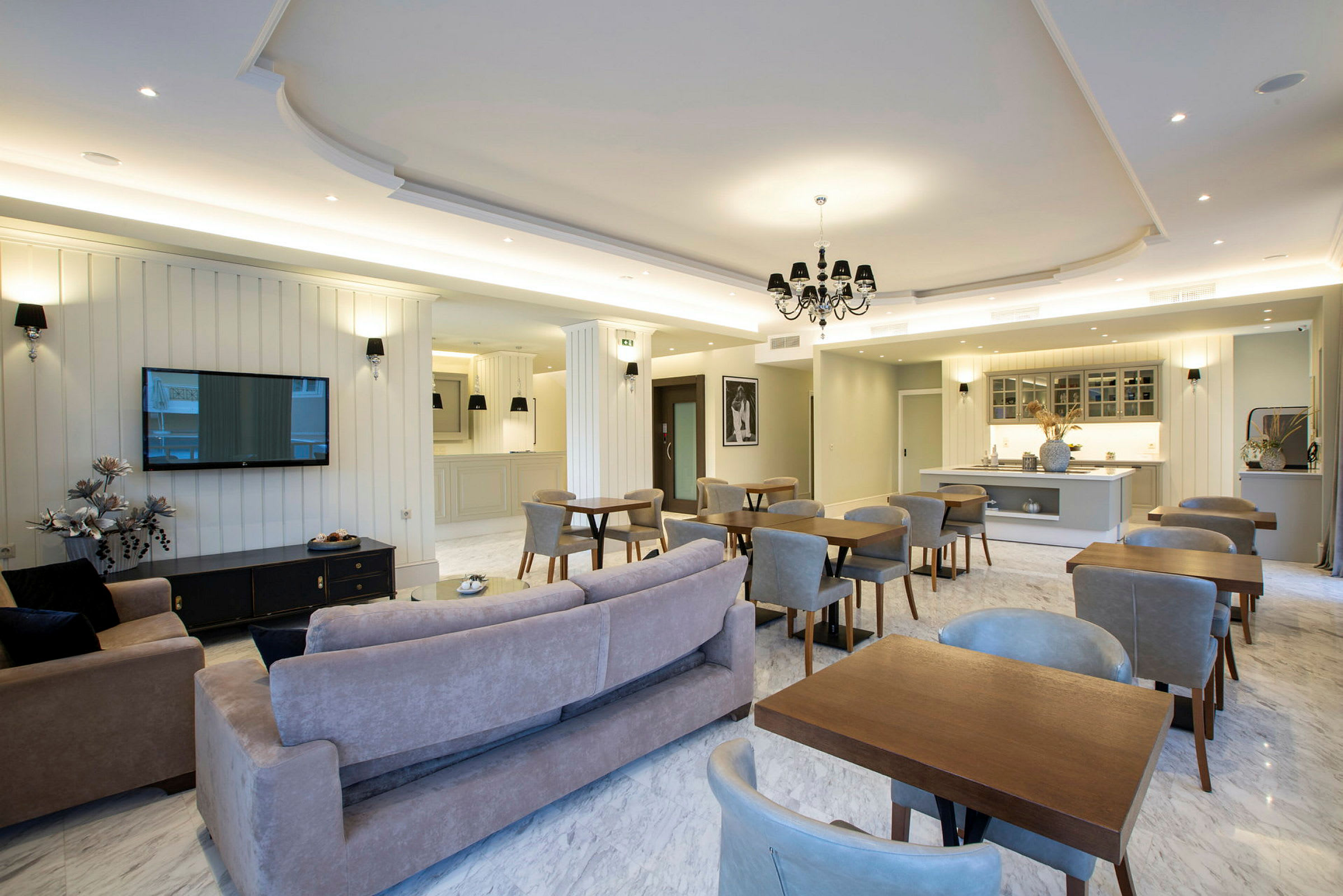 En rummelig indendørs lounge med siddegrupper og et køkkenområde i elegant moderne stil. (AI-genereret tekst)