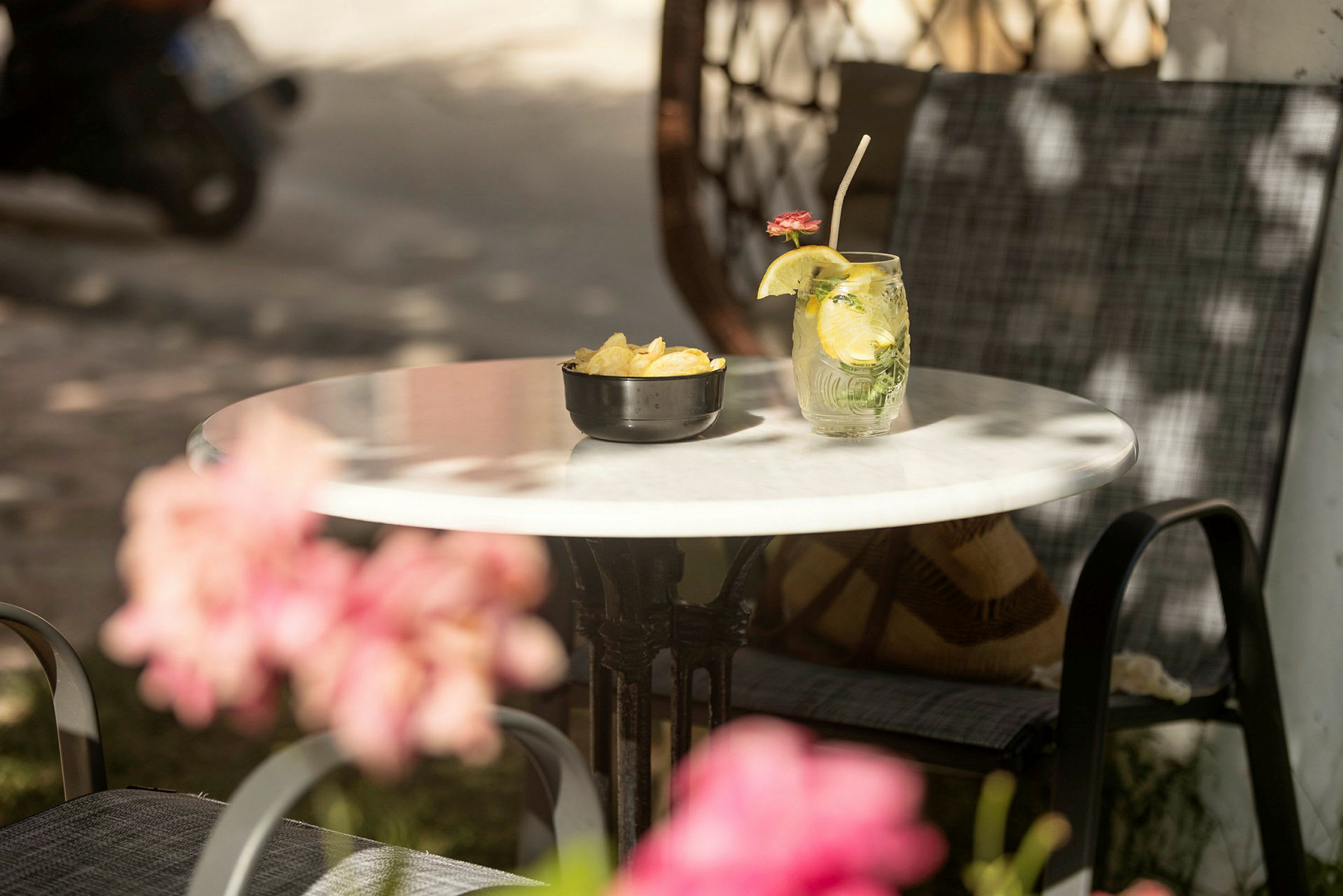 Et bord med en skål chips og et glas med en drink dekoreret med en citronskive og en blomst. (AI-genereret tekst)