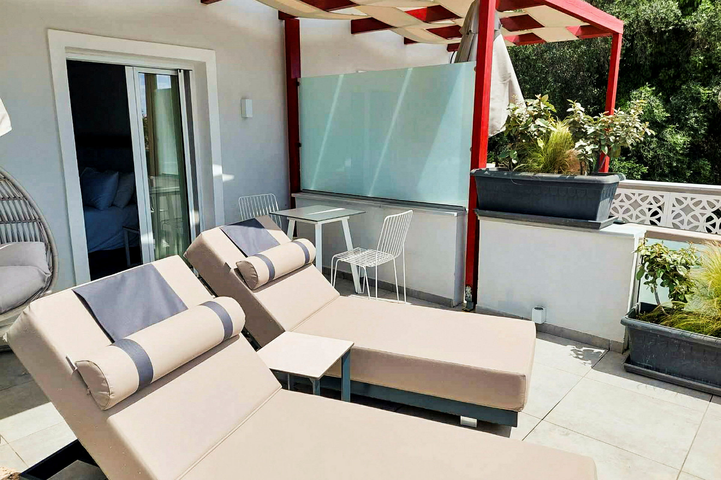Terrasse med to solsenge og et bord med to stole under en pergola. (AI-genereret tekst)