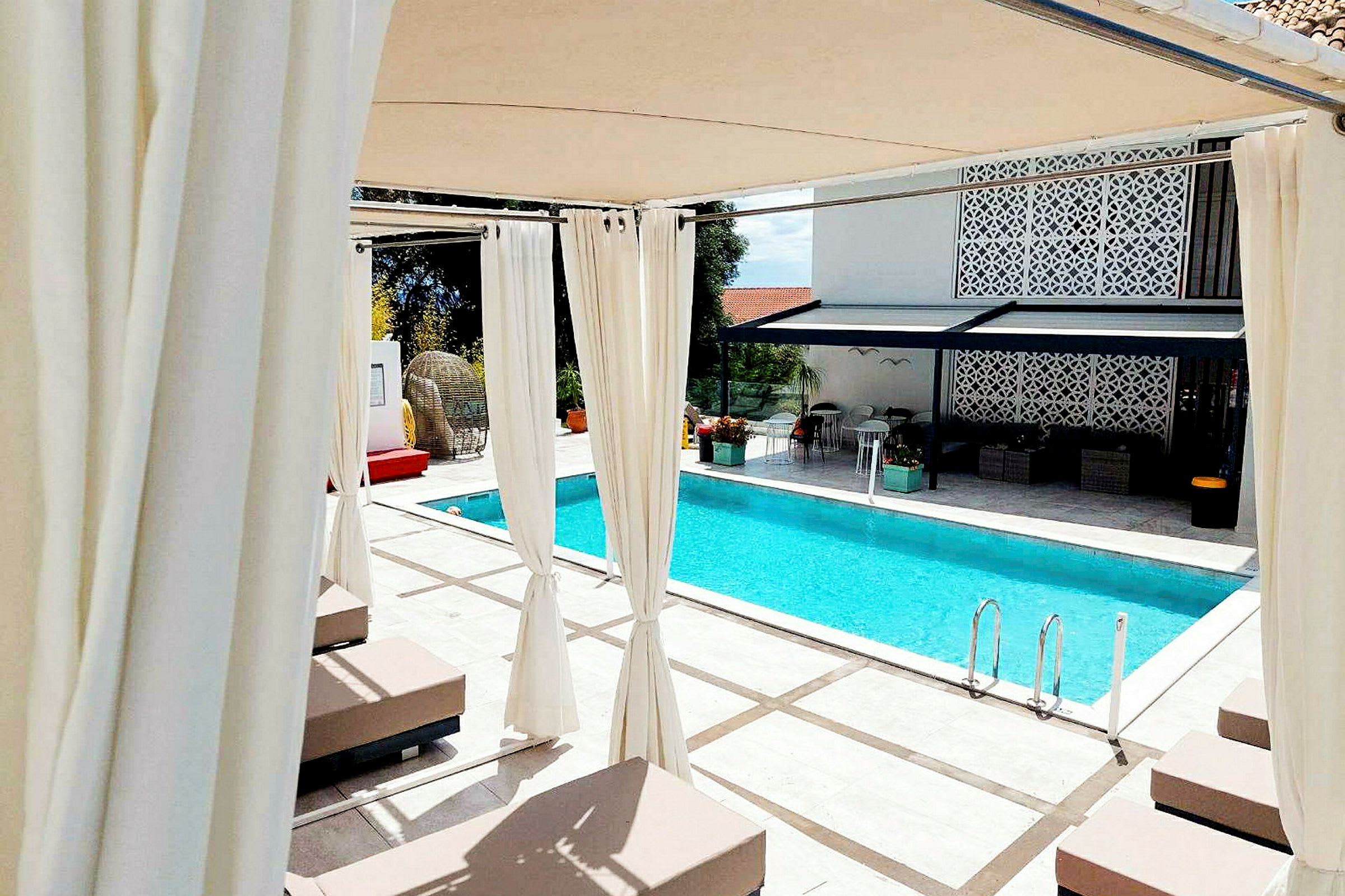Udendørs møbler ved en udendørs swimmingpool med liggestole og pergola. (AI-genereret tekst)