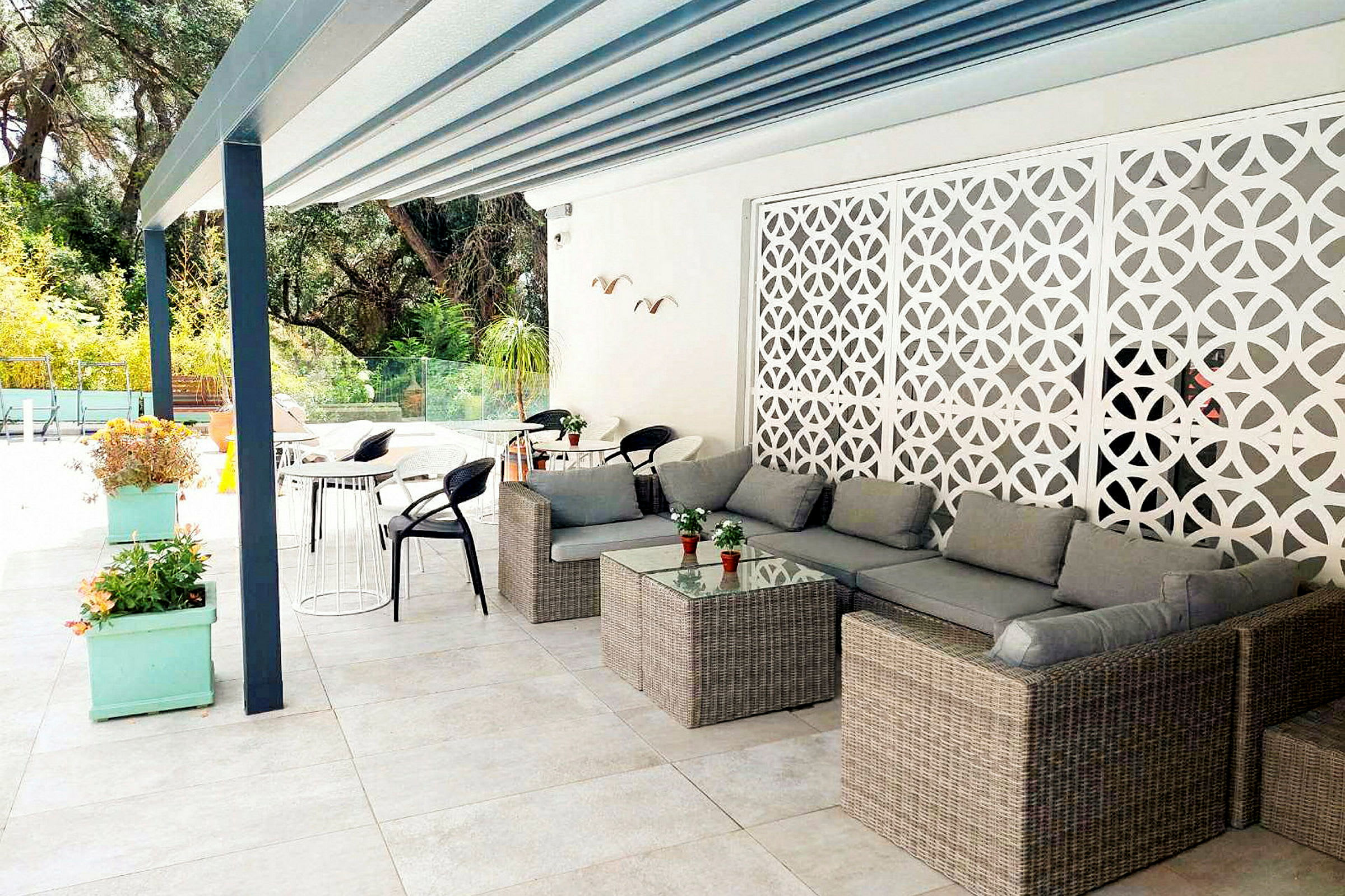 En terrasse med moderne møbler såsom sofaer, borde og stole samt dekorative elementer og beplantning. (AI-genereret tekst)