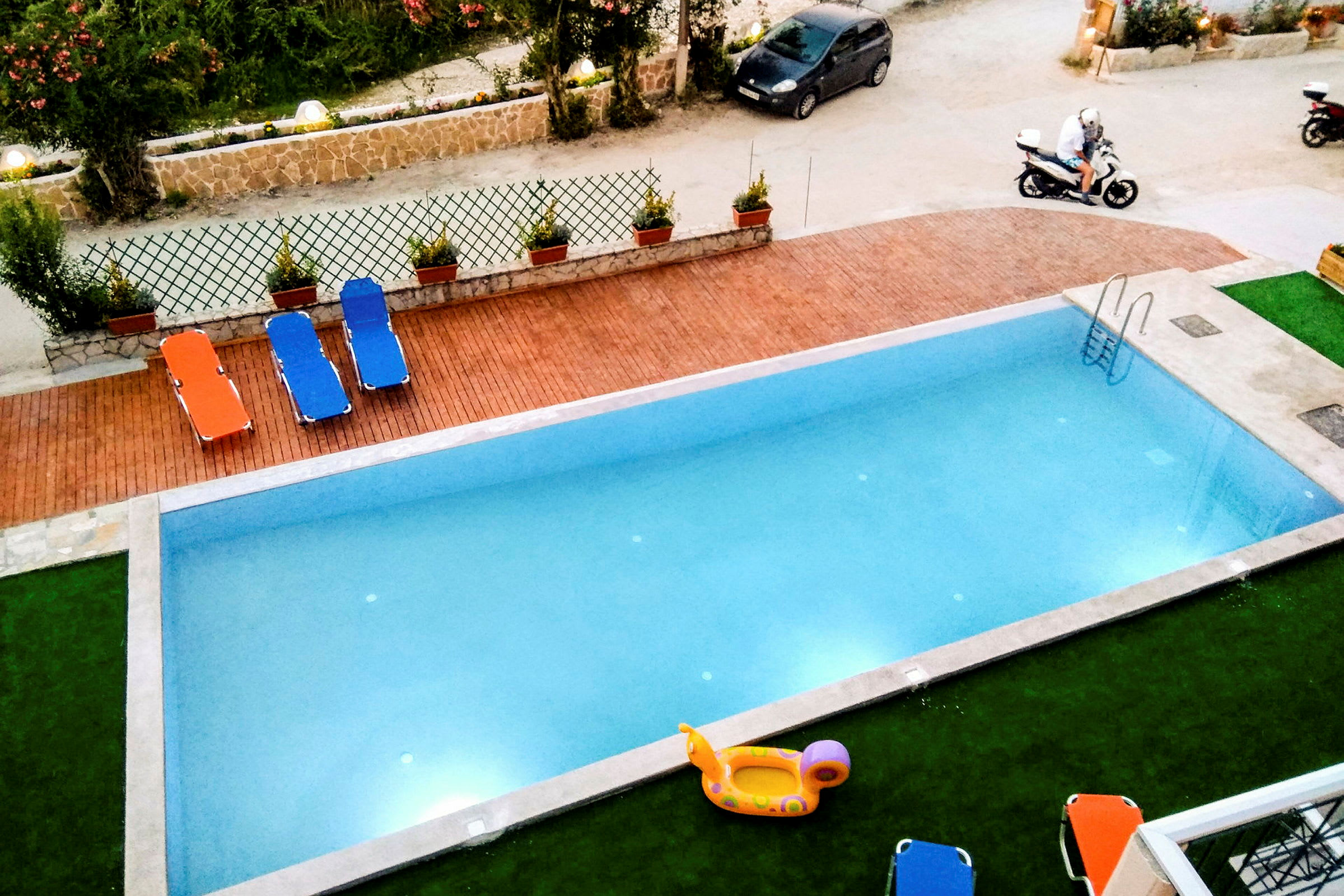 Udendørs swimmingpool med liggestole og oppusteligt legetøj. (AI-genereret tekst)