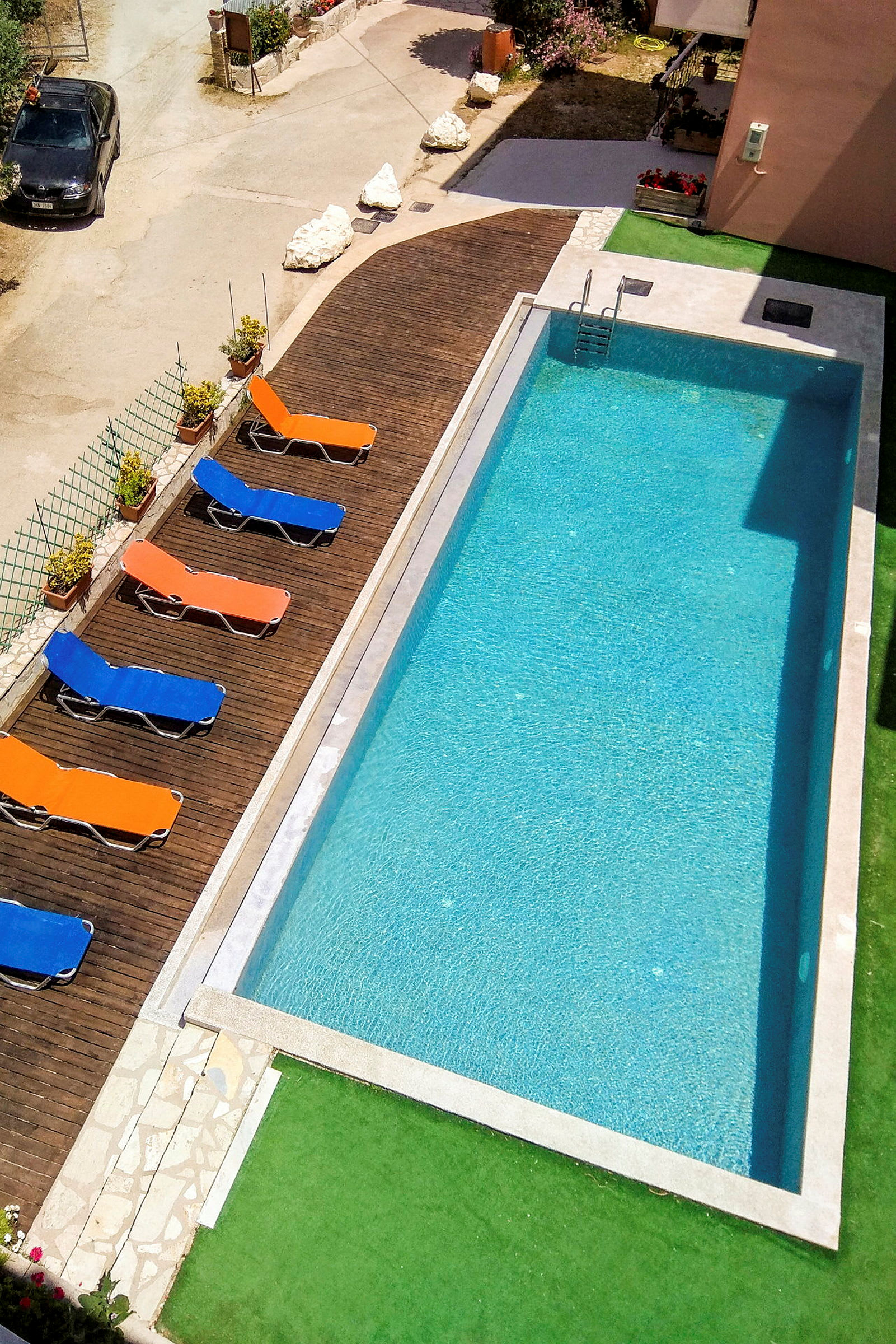 Bagsiden af en bil i et udendørs miljø med en swimmingpool og liggestole ved siden af. (AI-genereret tekst)