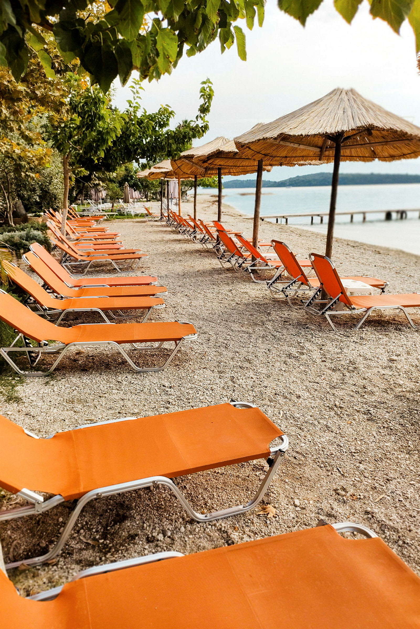 Strand med orange solsenge og parasoller. (AI-genereret tekst)