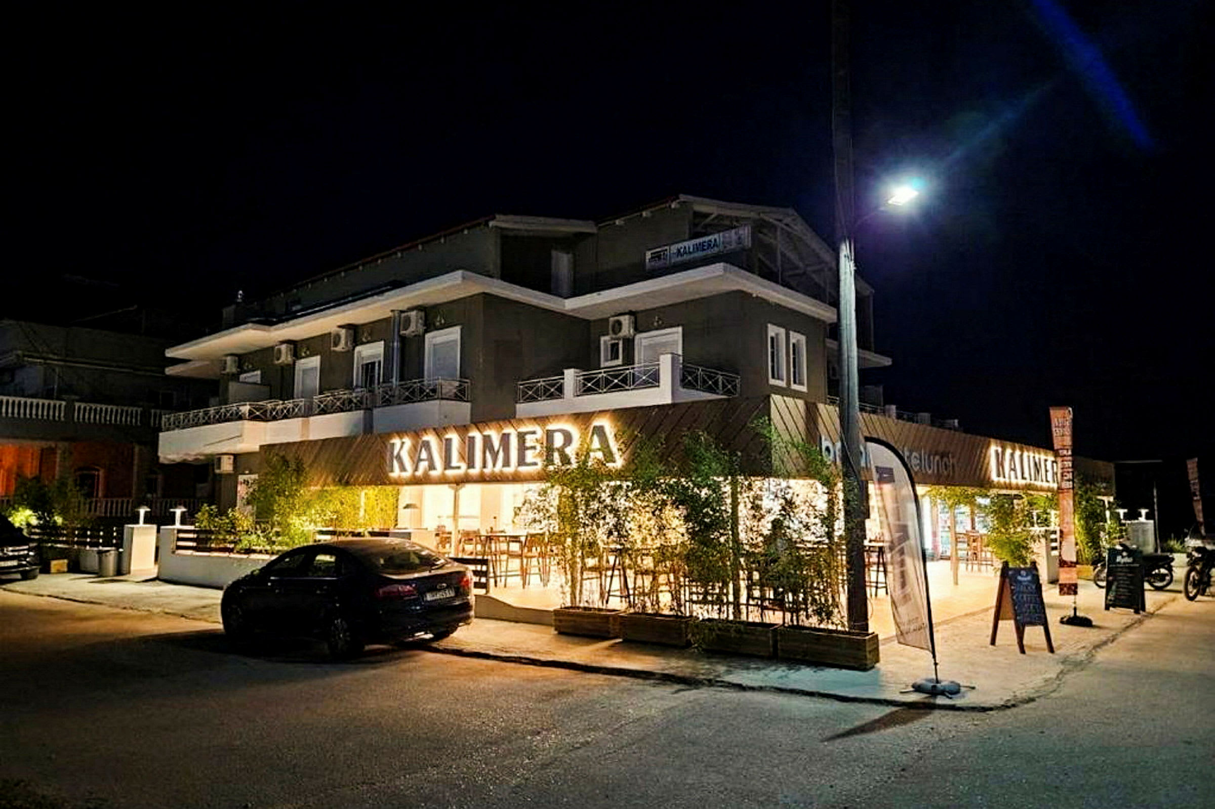En bygning med skiltet 'KALIMERA', fotograferet om aftenen. (AI-genereret tekst)