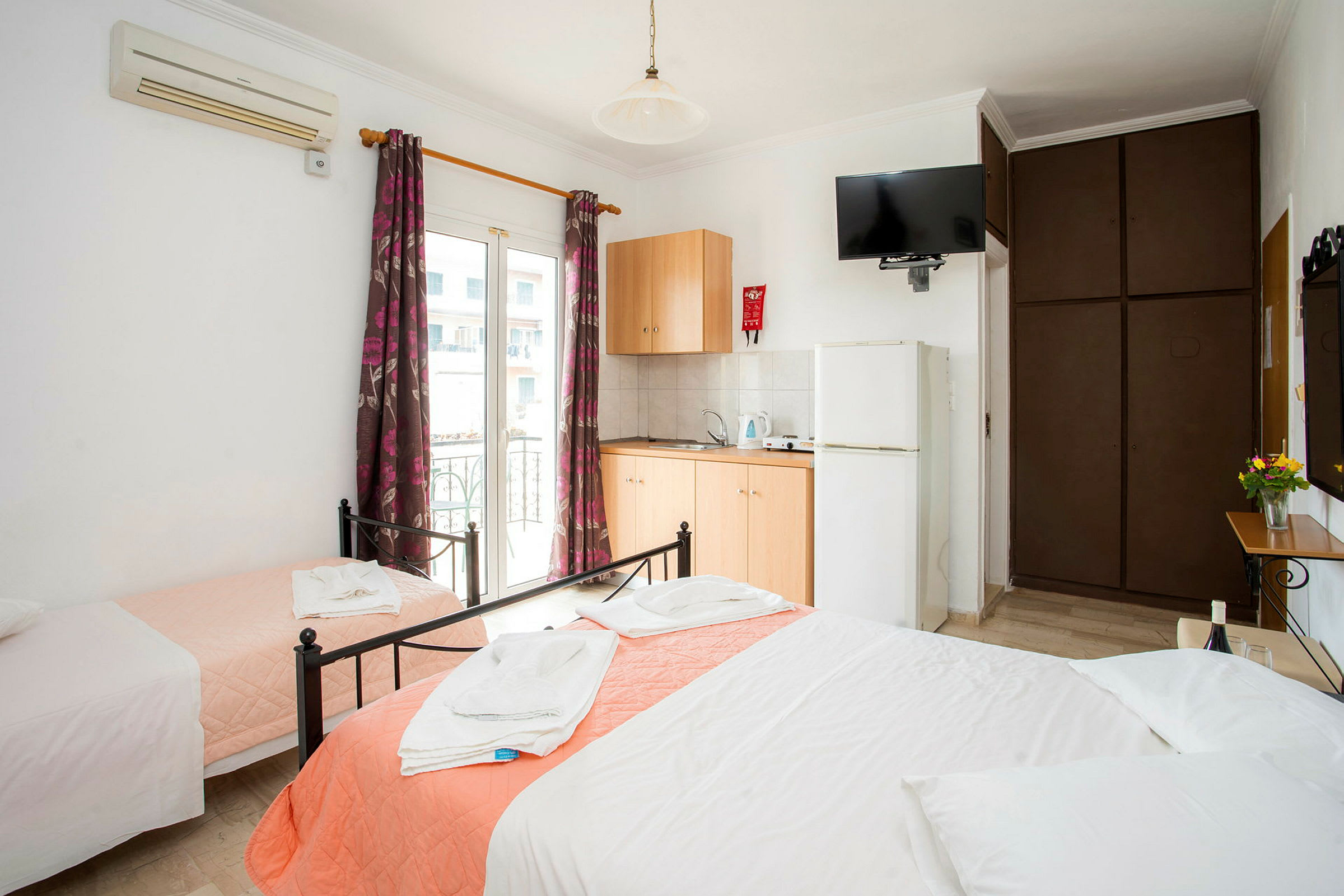 Hotelværelse med tre senge, garderobe, aircondition og tekøkken. (AI-genereret tekst)