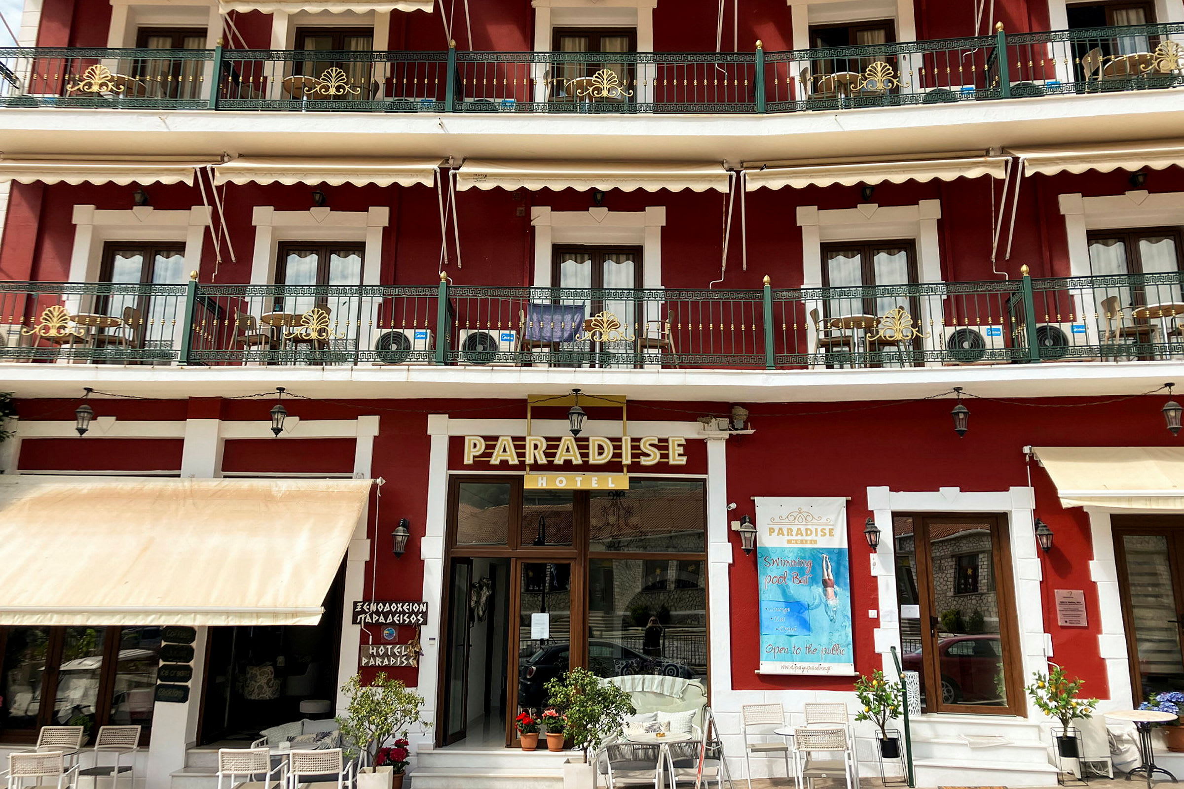 To etager af Paradise-hotellet i en rød bygning med altaner og hvid udsmykning. (AI-genereret tekst)