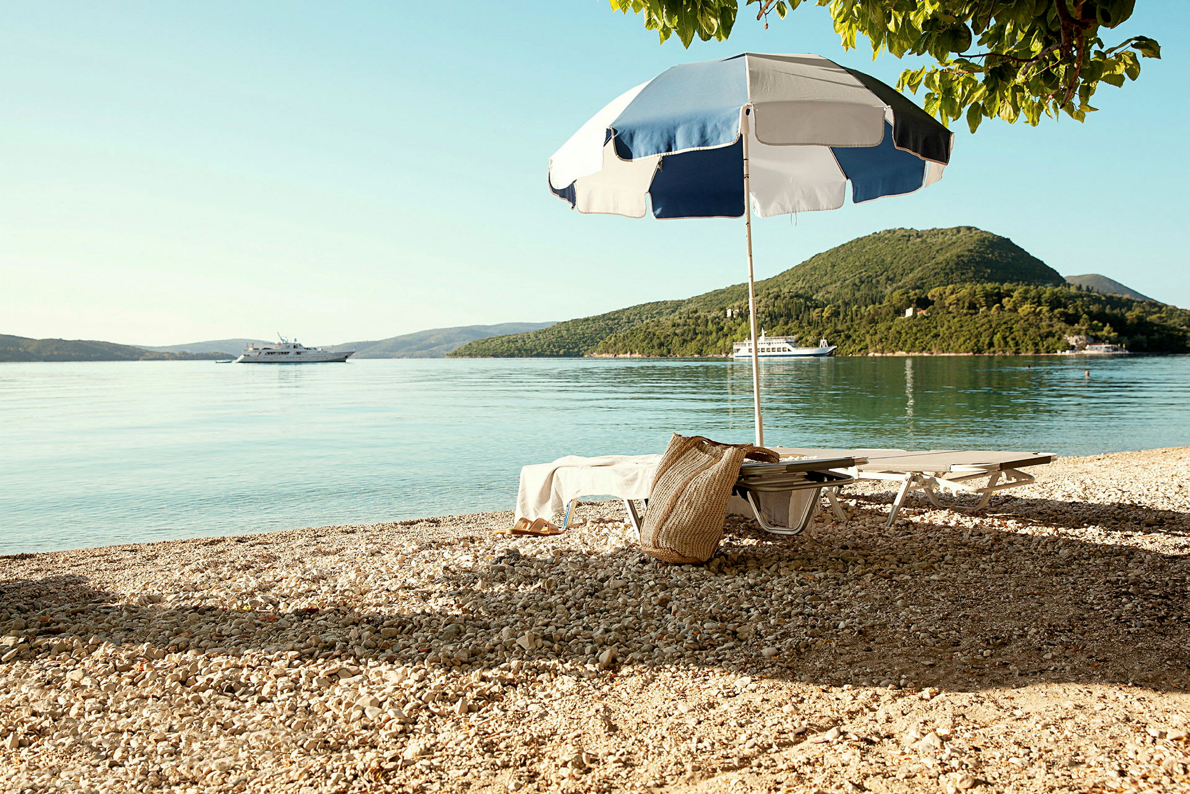Strand med solsenge, parasol og en båd på vandet. (AI-genereret tekst)