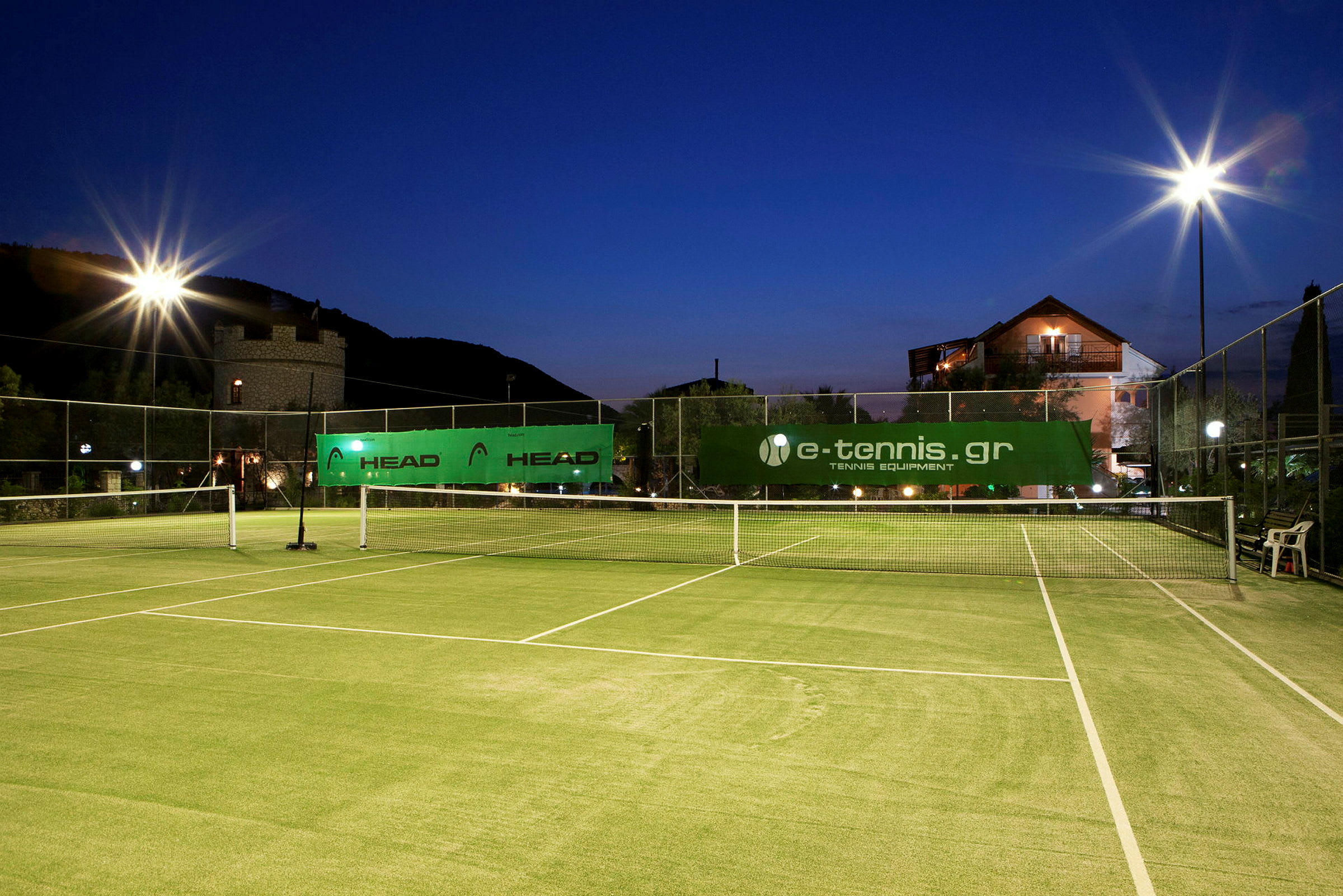 En udendørs tennisbane med belysning ved skumring. (AI-genereret tekst)